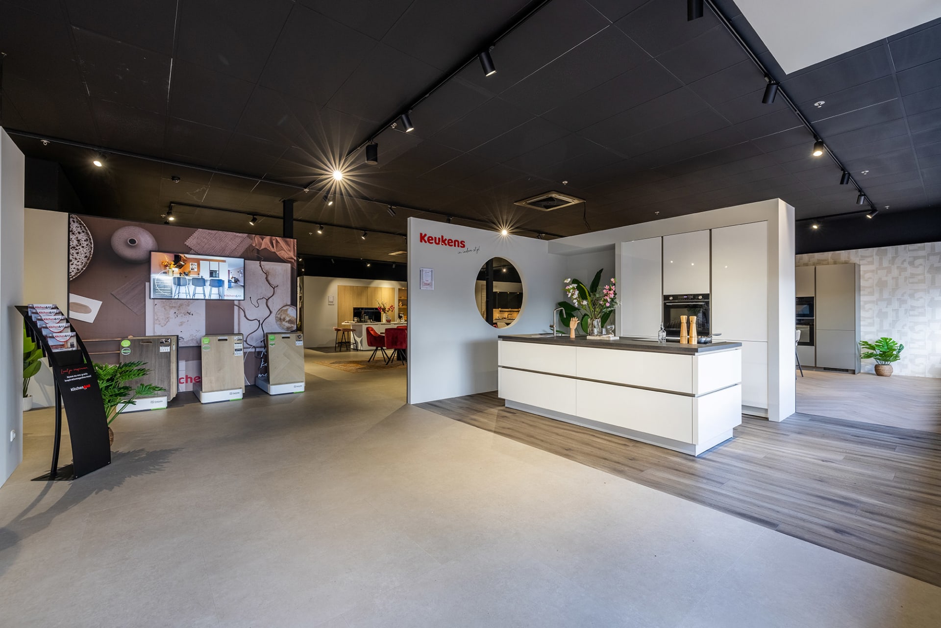 Het entreegedeelte van de Kitchen4All-winkel met stalendisplays en een witte keukenopstelling