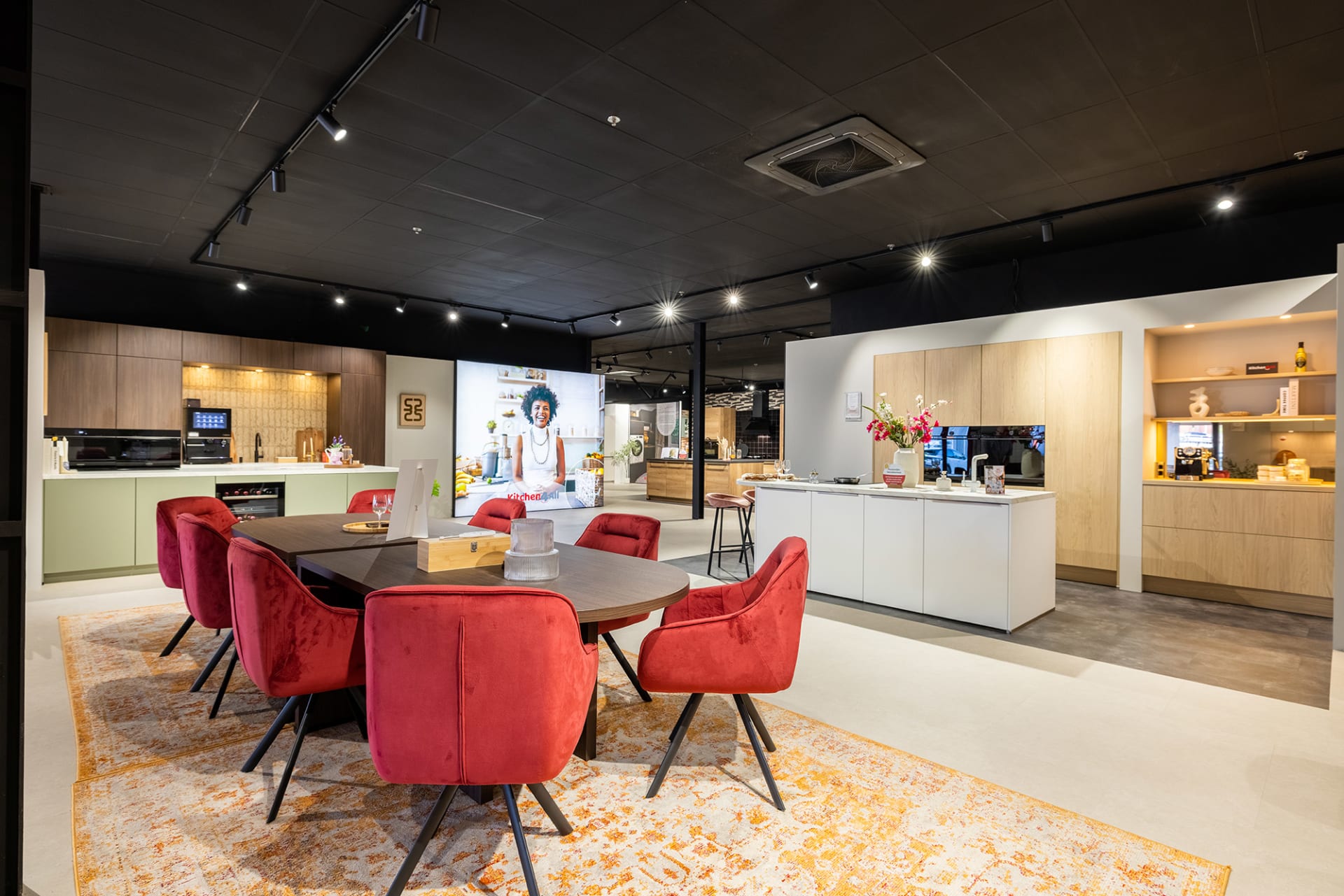 Ruim winkelinterieur met adviestafel, saliegroene keukenopstelling en wit kookeiland