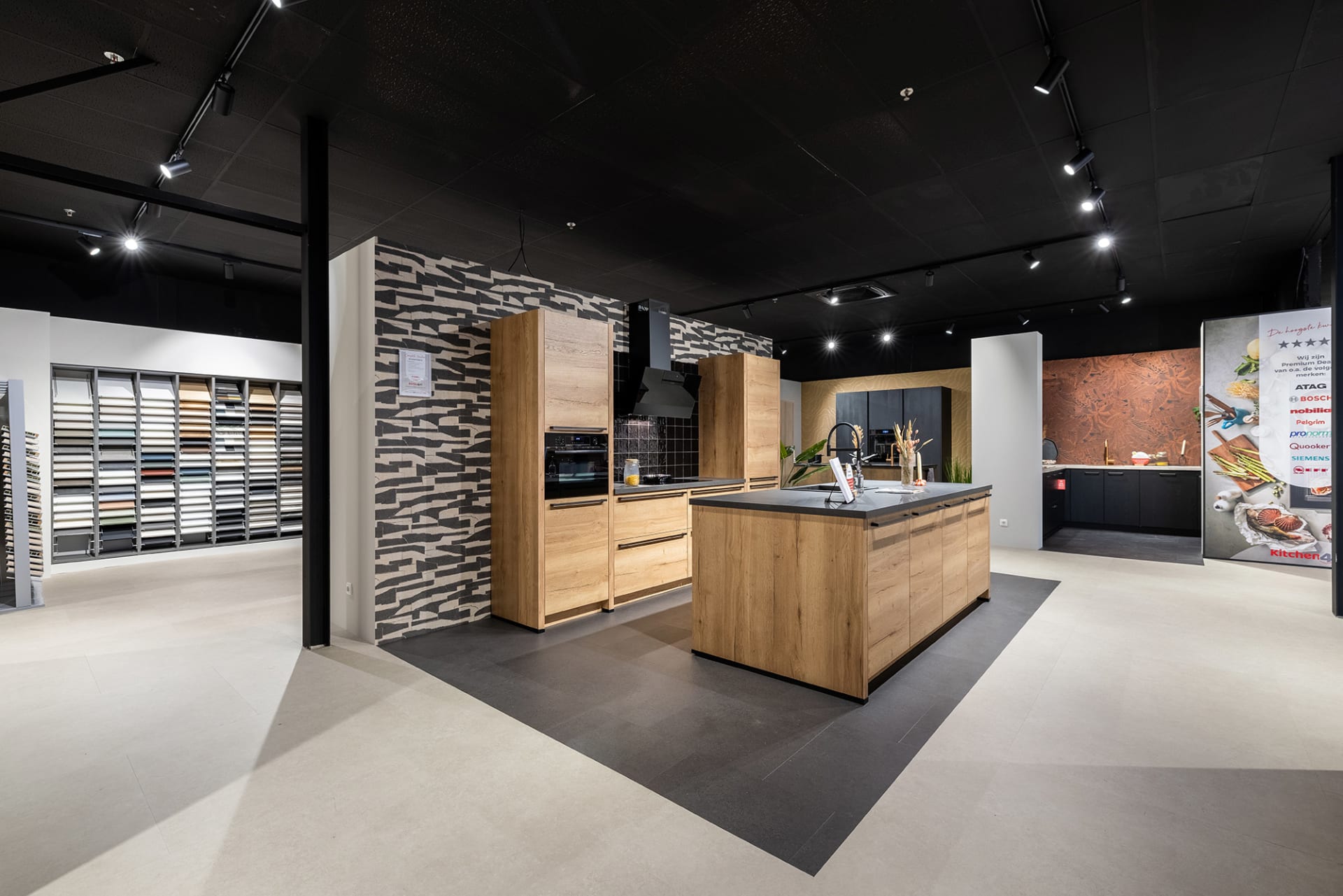 Eiken kookeiland met donker werkblad tussen de keukenopstellingen in de Kitchen4All-winkel