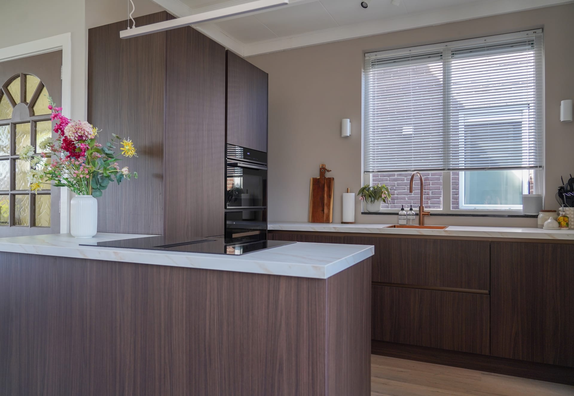 Overzicht van de keuken met kookeiland, kastenwand en houten vloer