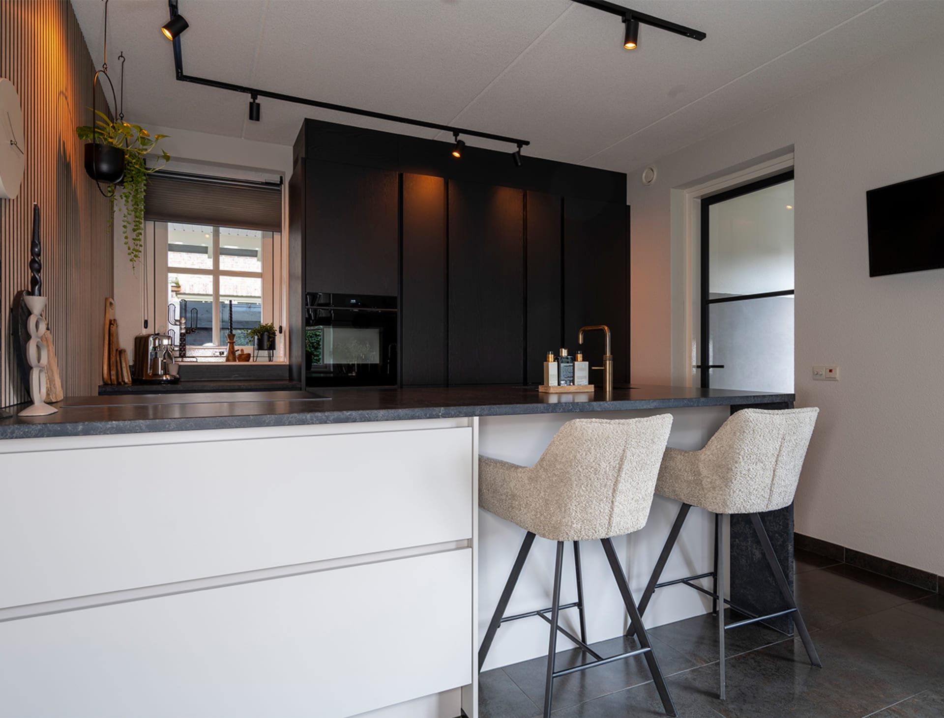 Lichte keuken met keukenbar, houten kastenwand en marmerlook werkblad