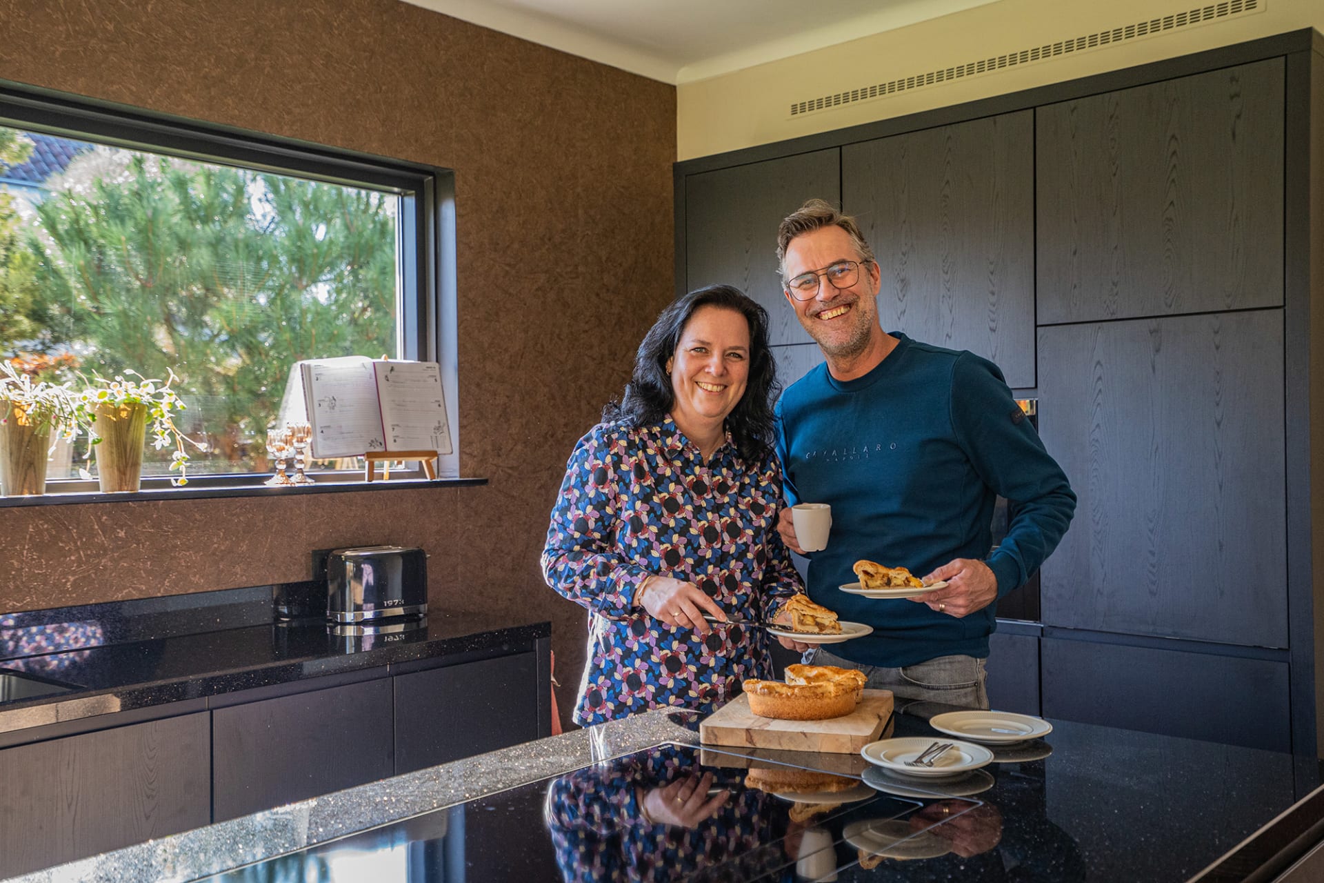 Rick en Bianca aan het zwarte kookeiland van hun donkere houtlook keuken