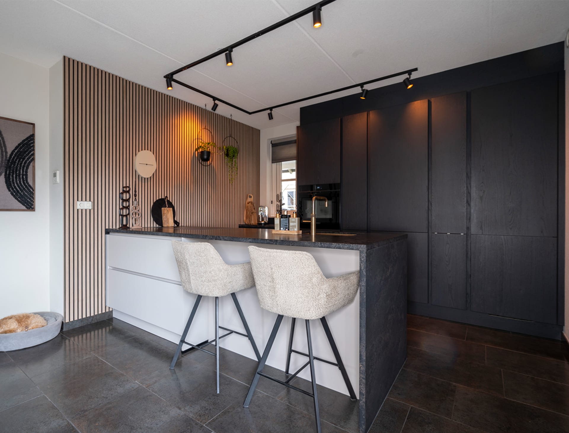 Woonkeuken met licht bareiland, donkere kastenwand en houten lattenwand