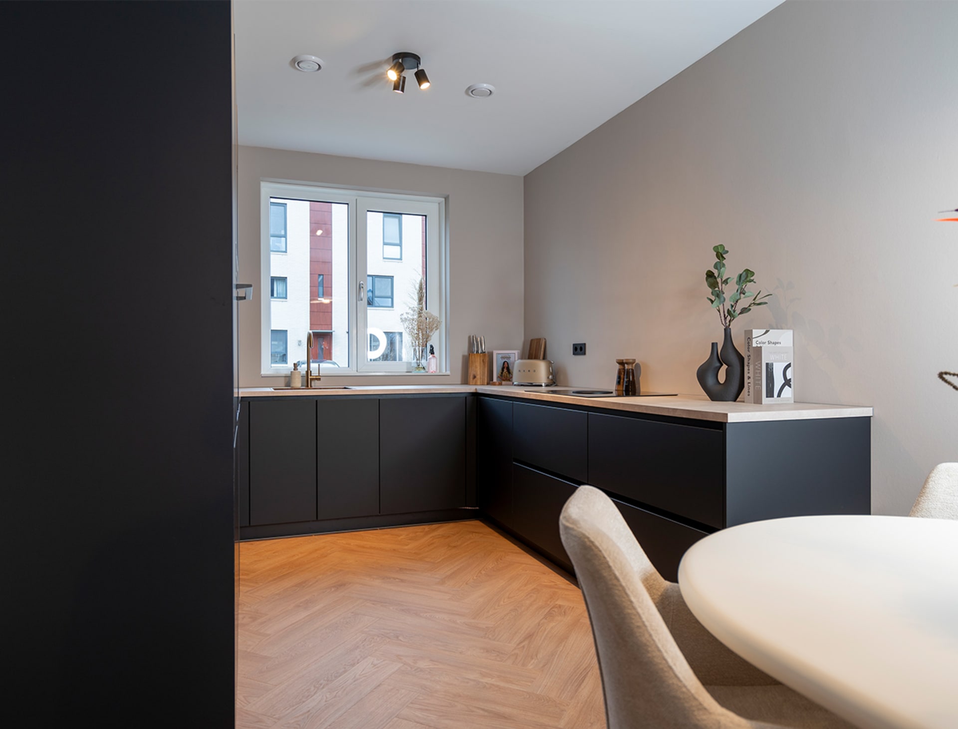 Moderne matzwarte hoekkeuken met visgraatvloer en eettafel