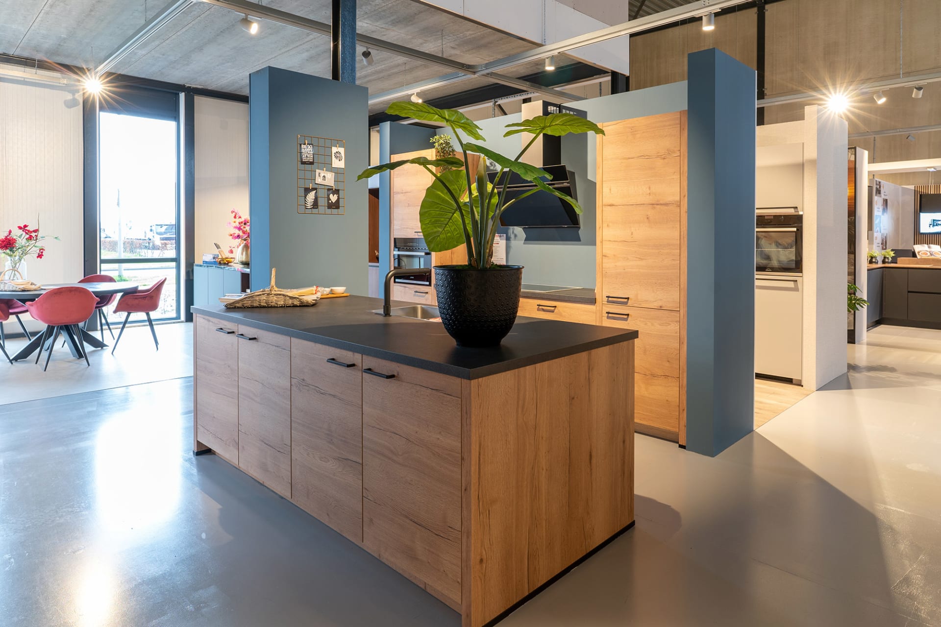 Houten kookeiland met zwart werkblad tussen de keukenopstellingen in de Kitchen4All-winkel