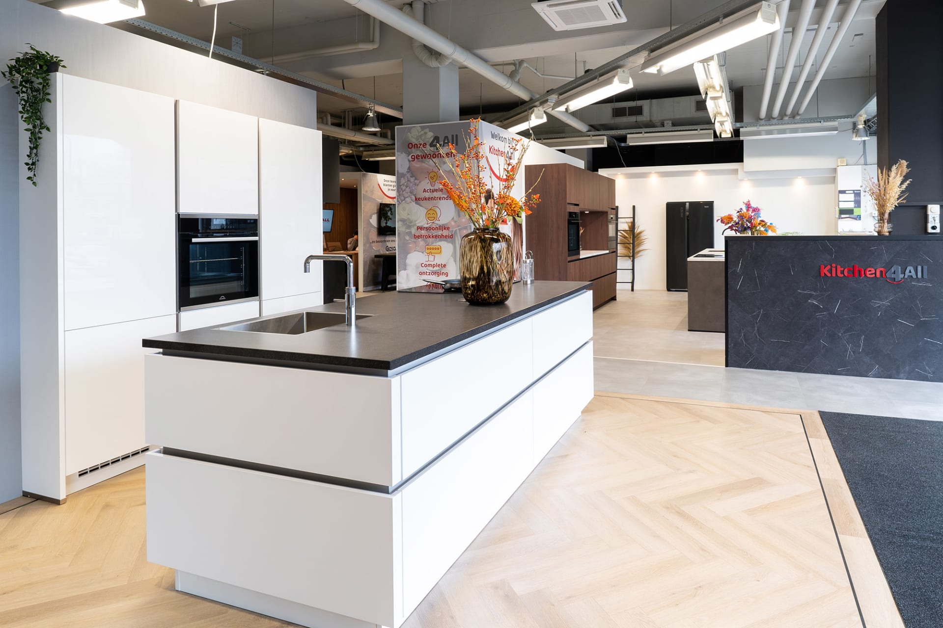 Wit kookeiland op een visgraatvloer in de ruime Kitchen4All-winkelhal