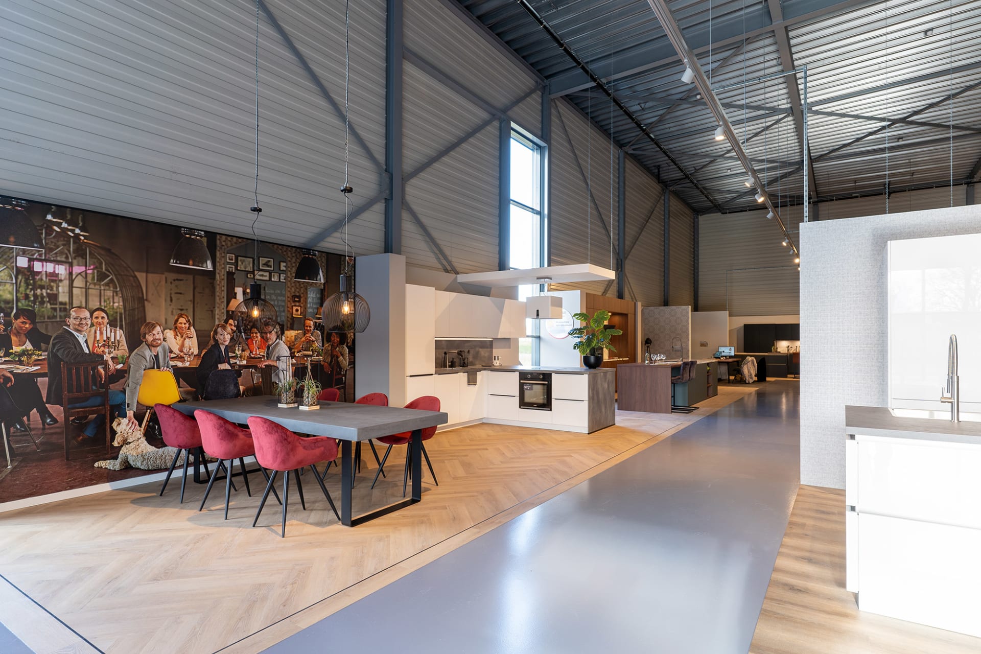 Ruime winkelhal van Kitchen4All met witte keukenopstelling en adviestafel met rode stoelen