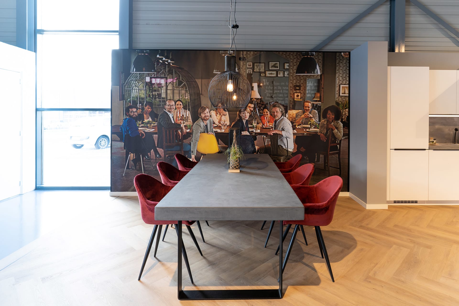 Adviestafel met bordeauxrode stoelen voor een grote fotowand in de Kitchen4All-winkel