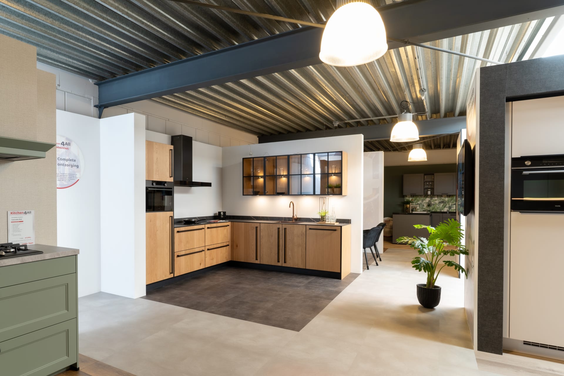 Houtlook hoekkeuken naast een groene keukenopstelling in de Kitchen4All-winkel