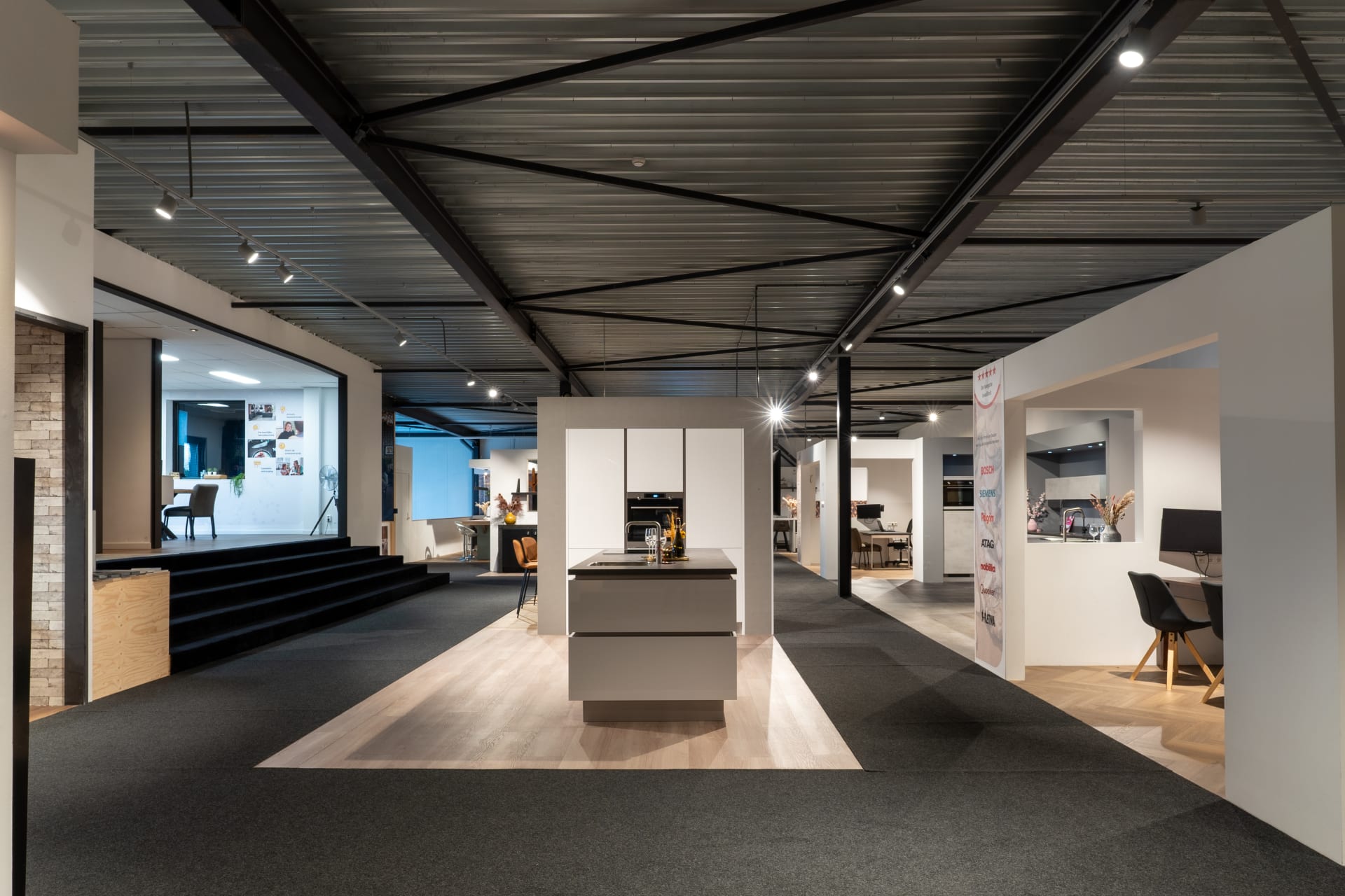 Doorkijk door de Kitchen4All-winkel met een wit kookeiland en presentatiewanden