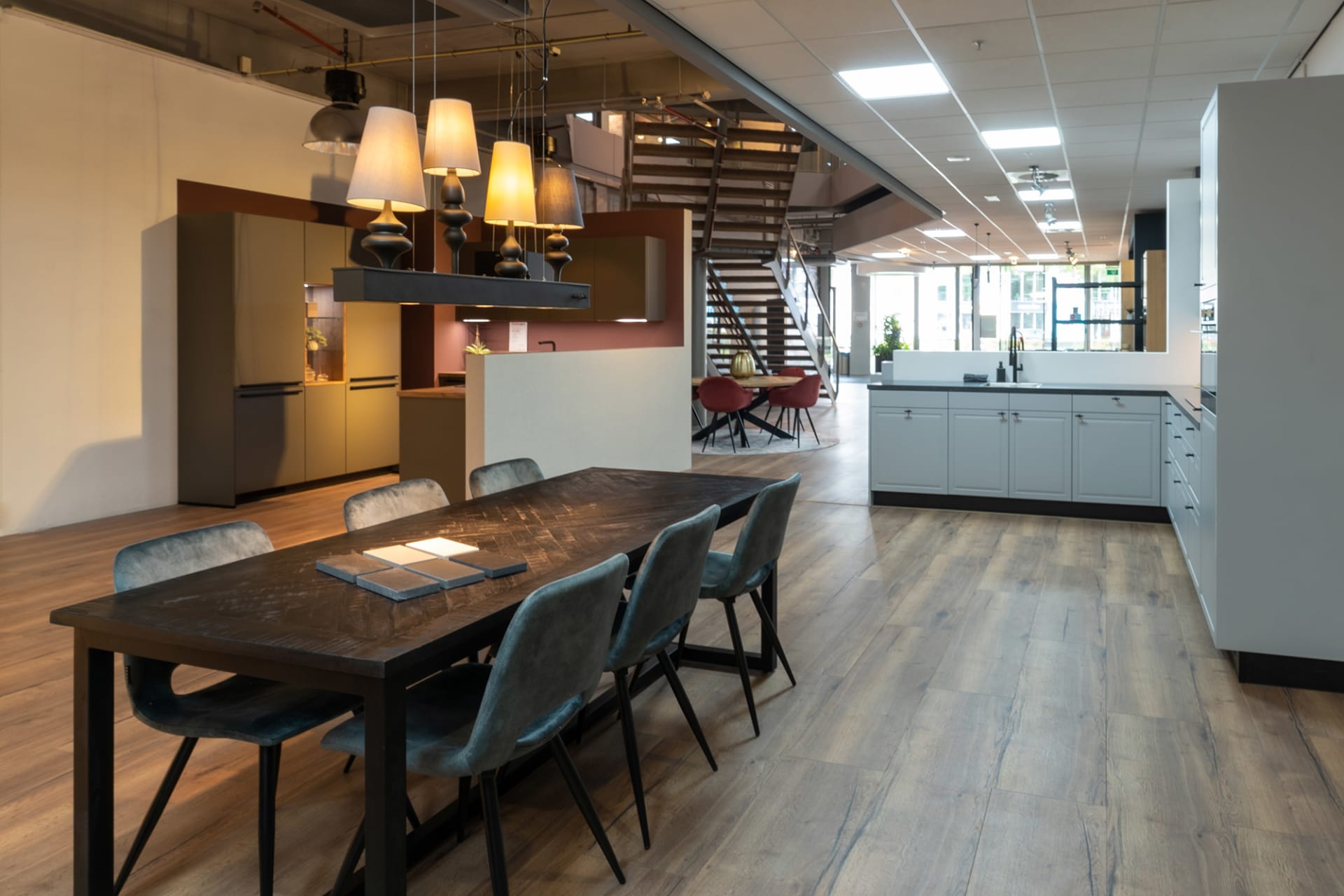 Houten eettafel bij een grijsblauwe keukenopstelling in de Kitchen4All-winkel