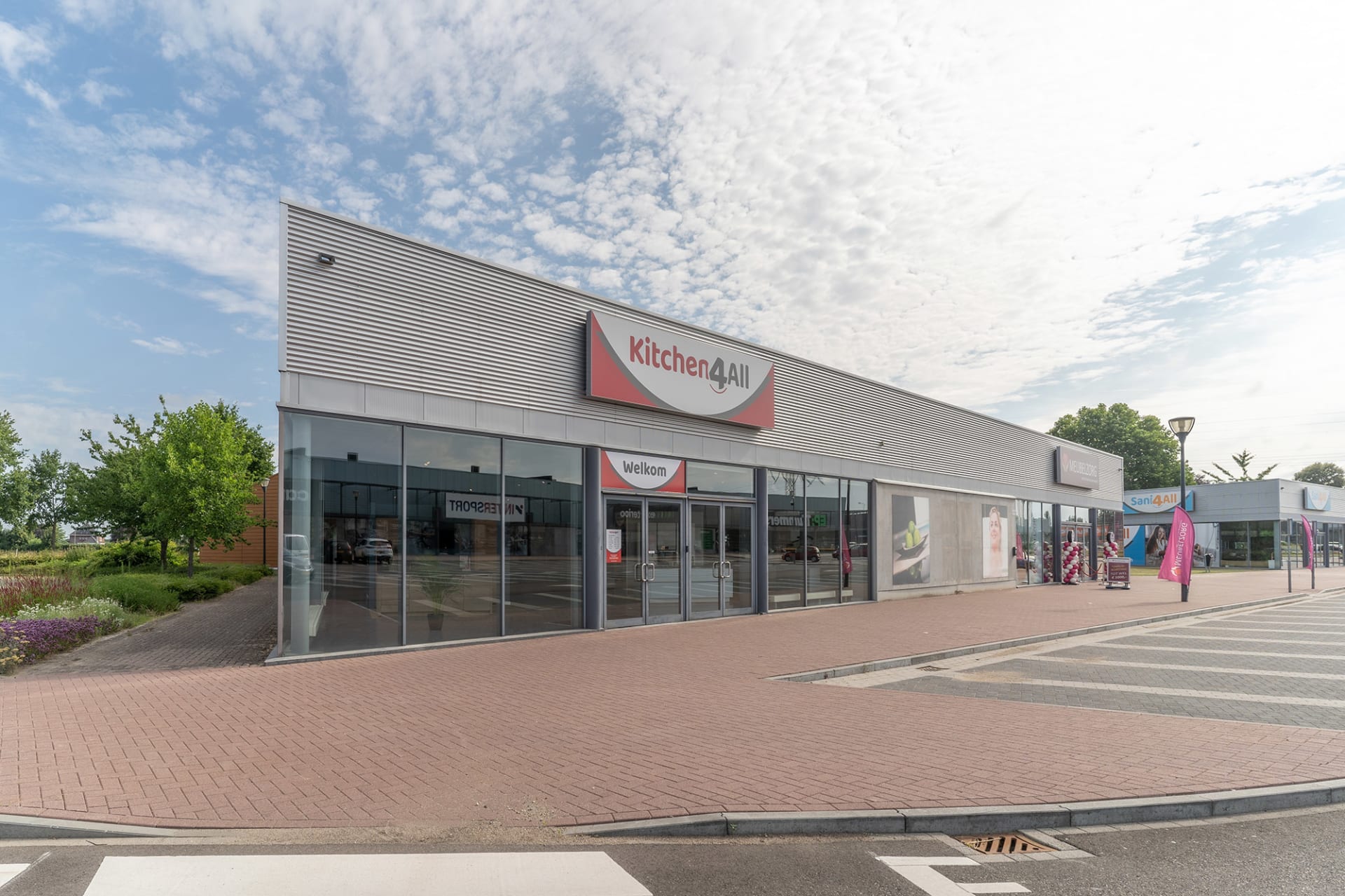 Zijaanzicht van de Kitchen4All-winkel met parkeerplaats voor de deur