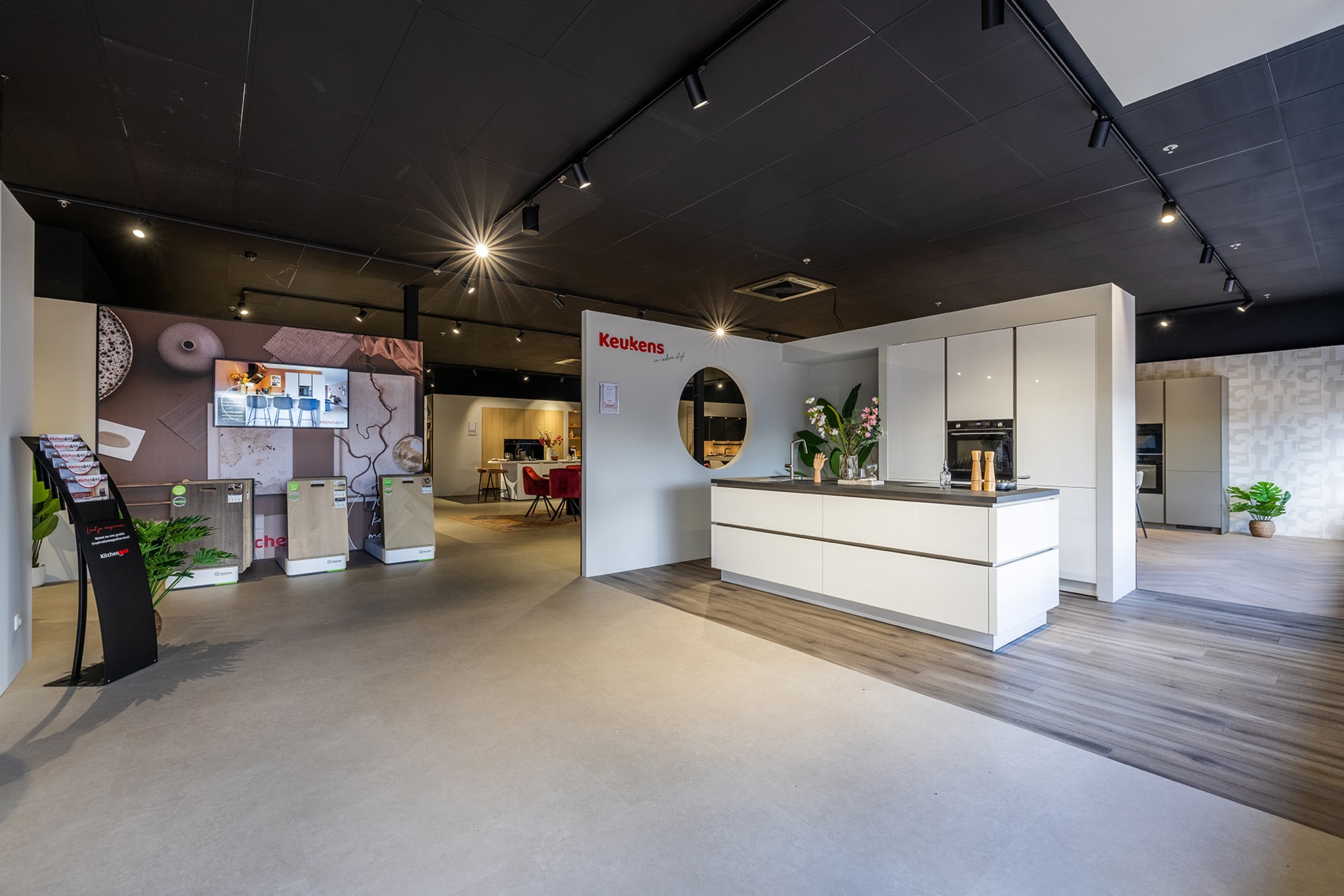 Het entreegedeelte van de Kitchen4All-winkel met stalendisplays en een witte keukenopstelling
