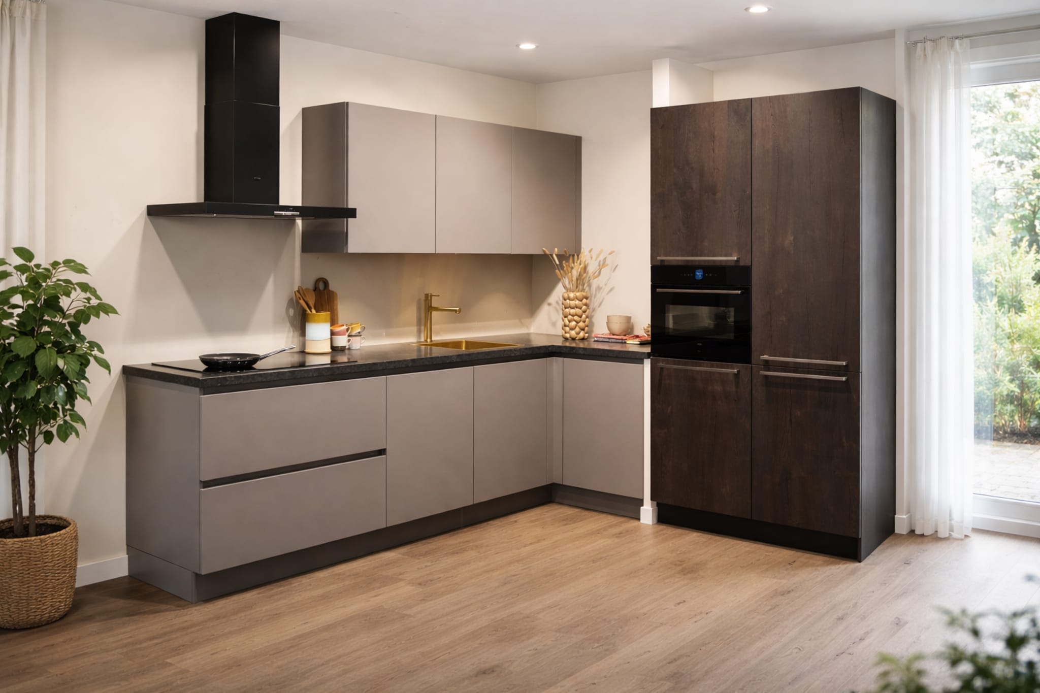 Moderne Kitchen4All L-keuken met matgrijze greeploze fronten, donker keramiek werkblad en houtlook kastenwand.