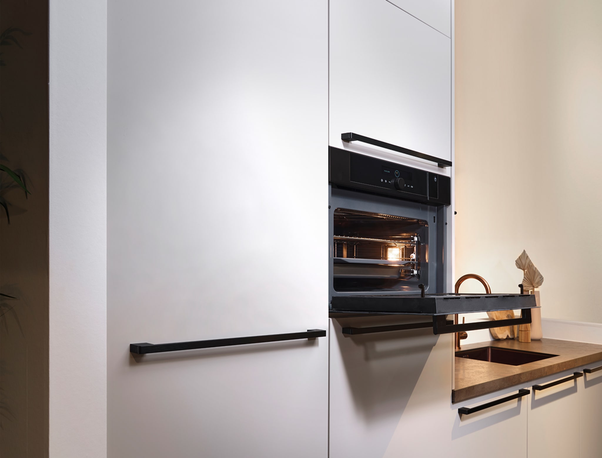 Moderne rechte keuken van Kitchen4All met witte matte fronten, zwarte handgrepen en een houten werkblad.