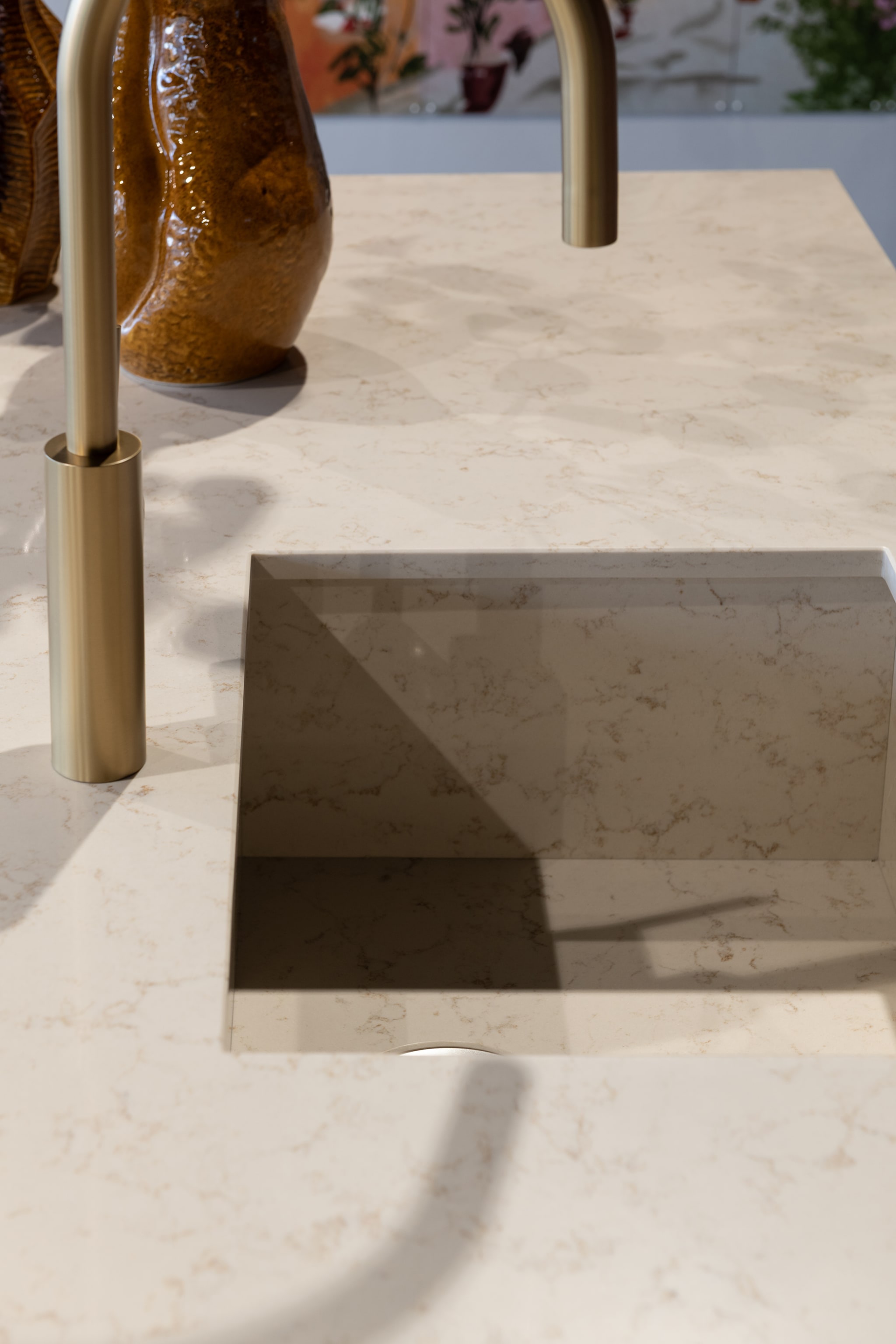 Close-up van een Boutique fris eilandkeuken met een wit composiet werkblad in marmerlook en een gouden kraan.