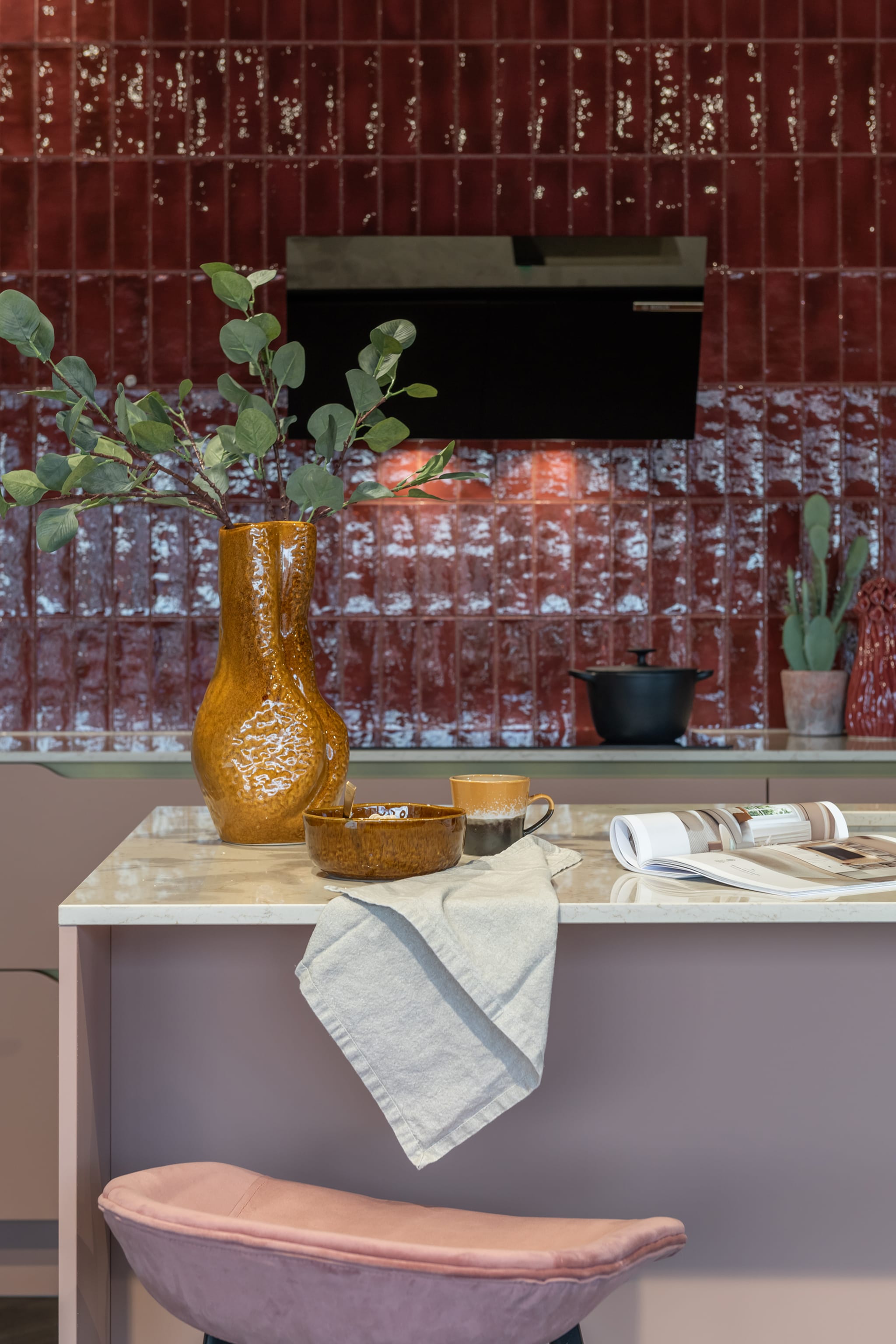 Modern Kitchen4All kookeiland met rood structuur front, zwart composiet werkblad en greeploze afwerking.