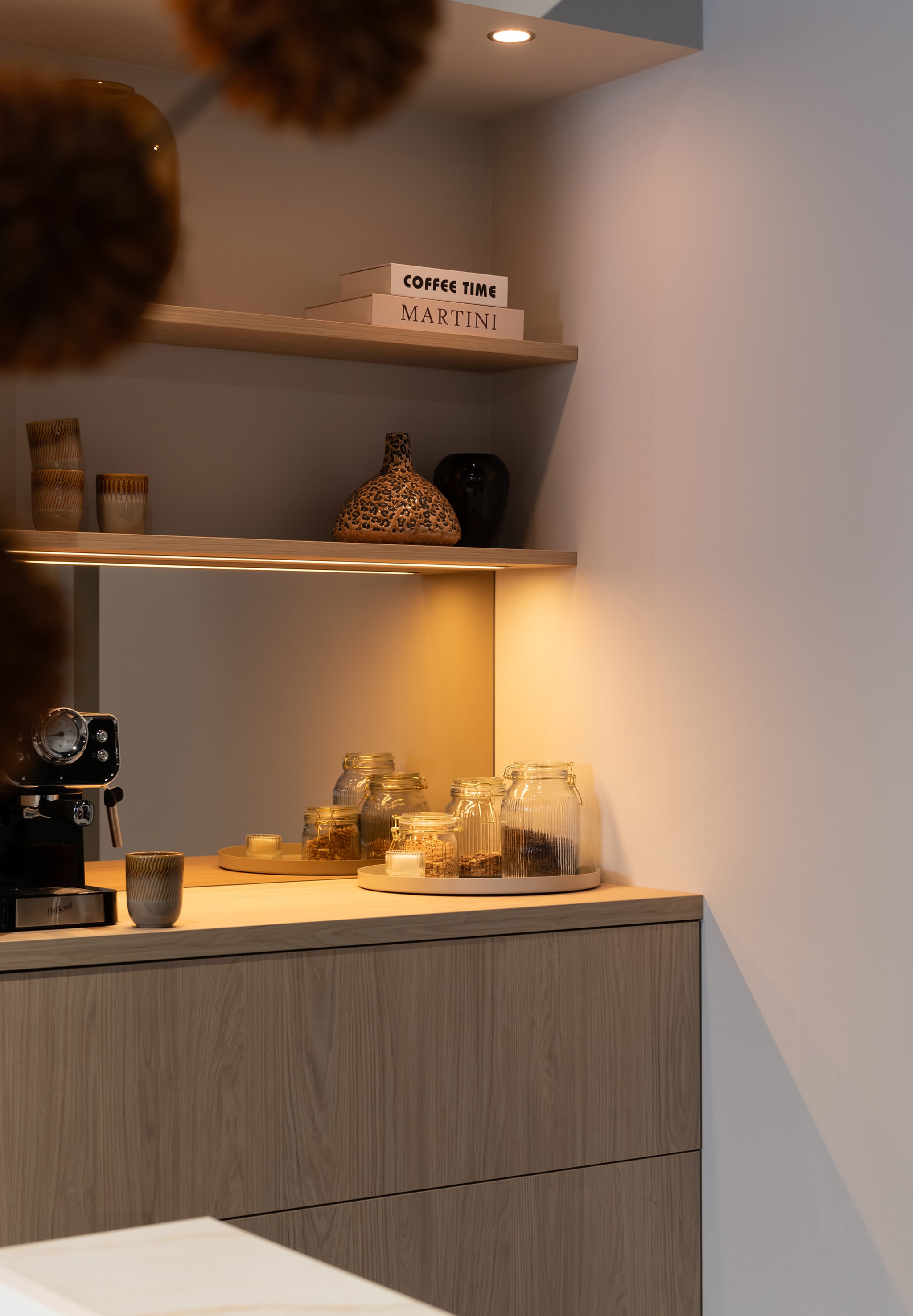 Een Scandi modern keuken met houtlook werkblad en greeploze houten fronten, verlicht door warme ledstrips.