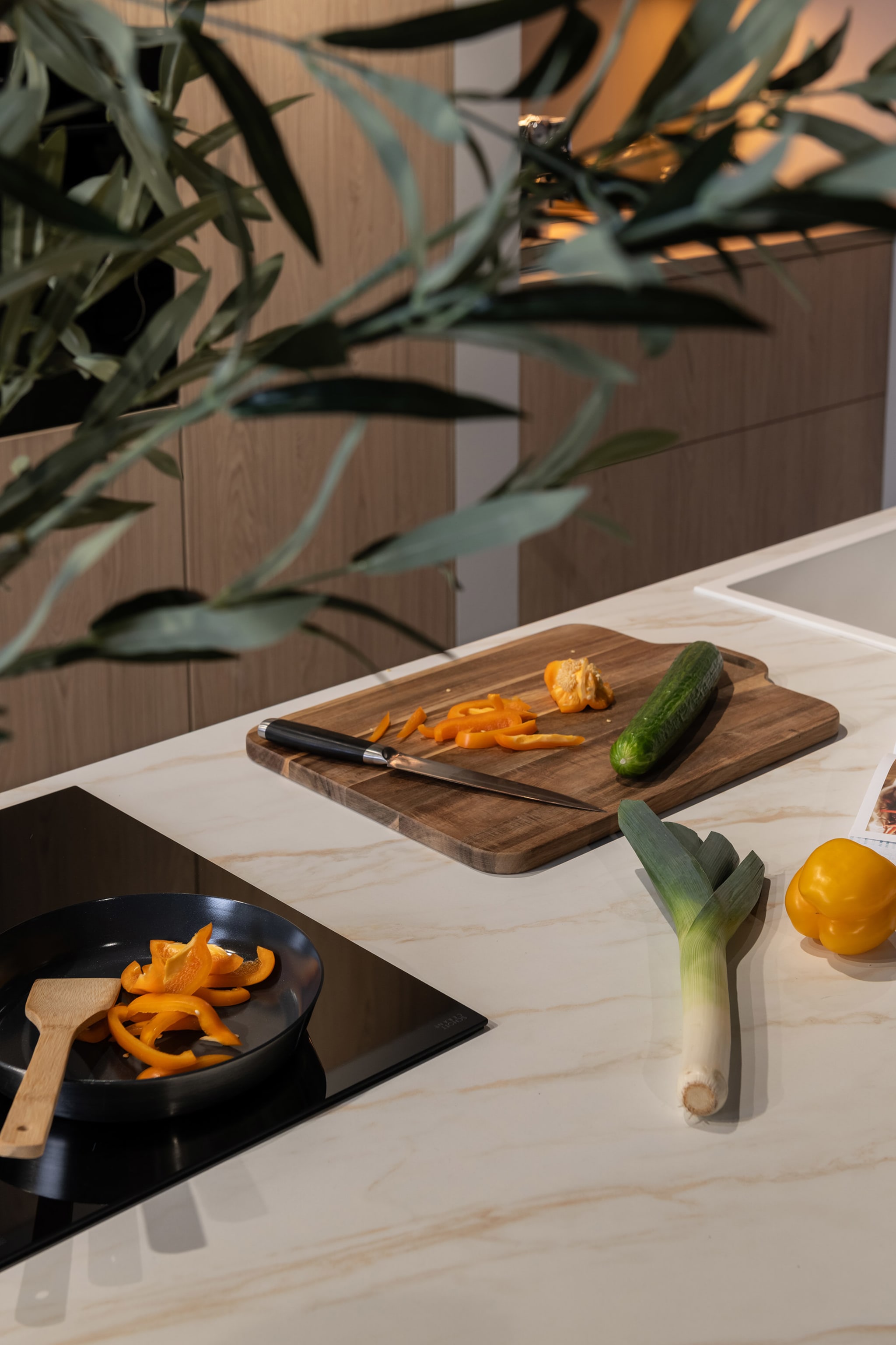 Een Scandi modern eilandkeuken met een wit composiet marmerlook werkblad en greeploze echt houten fronten.