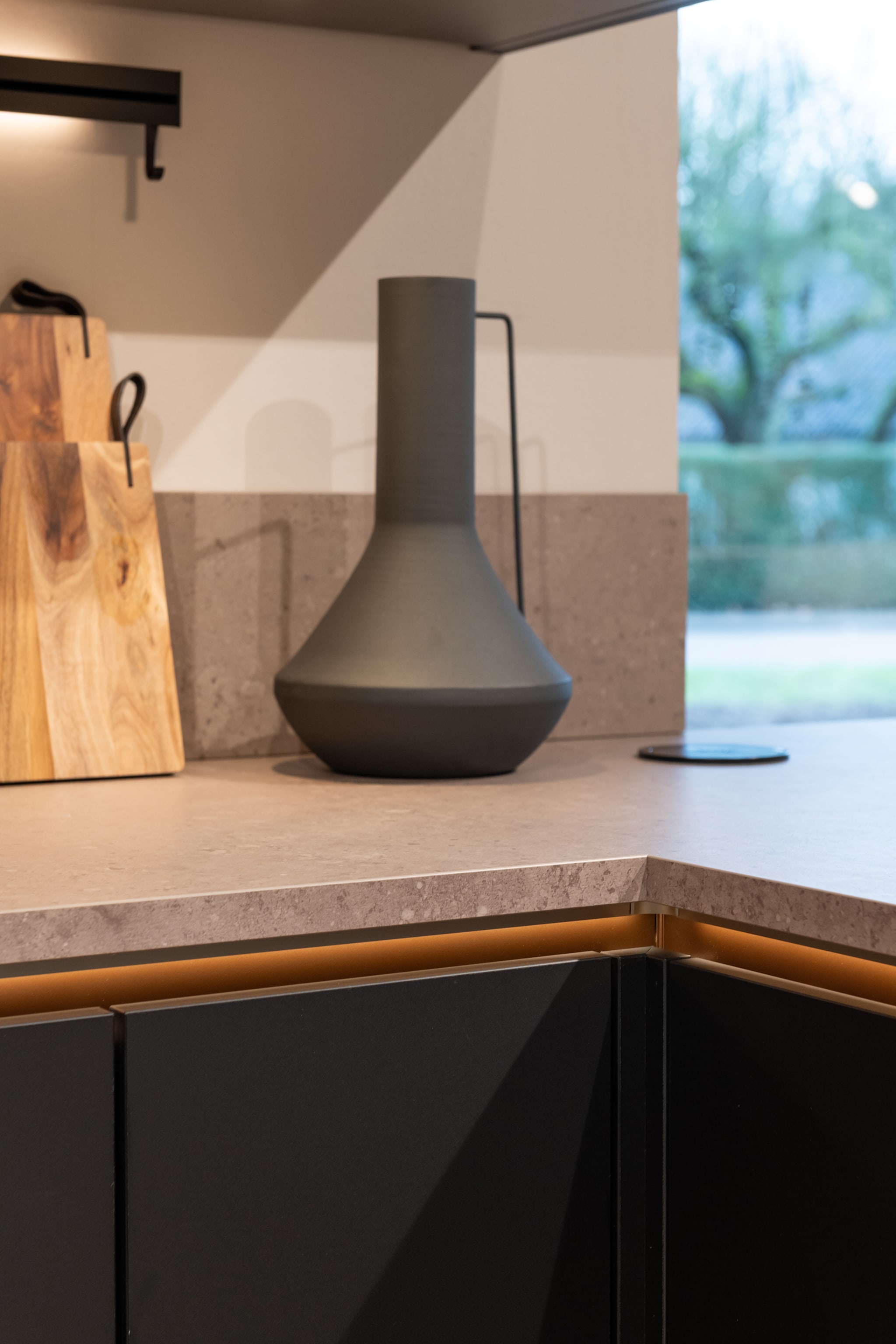 Moderne greeploze L-keuken met donker composiet werkblad en matzwarte fronten.