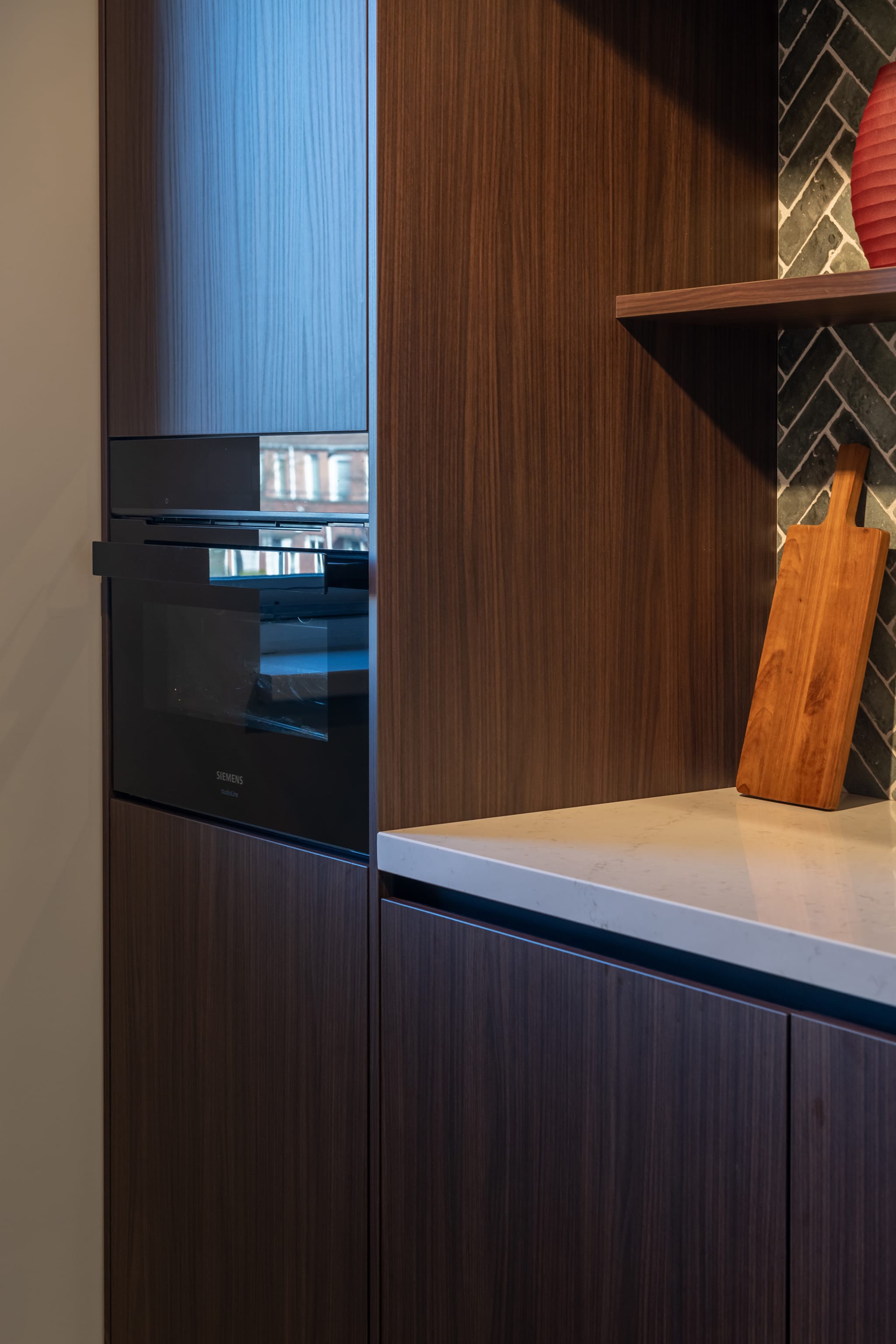 Moderne, greeploze Puur design keuken van Kitchen4All met donkere houttinten en een wit composiet werkblad.