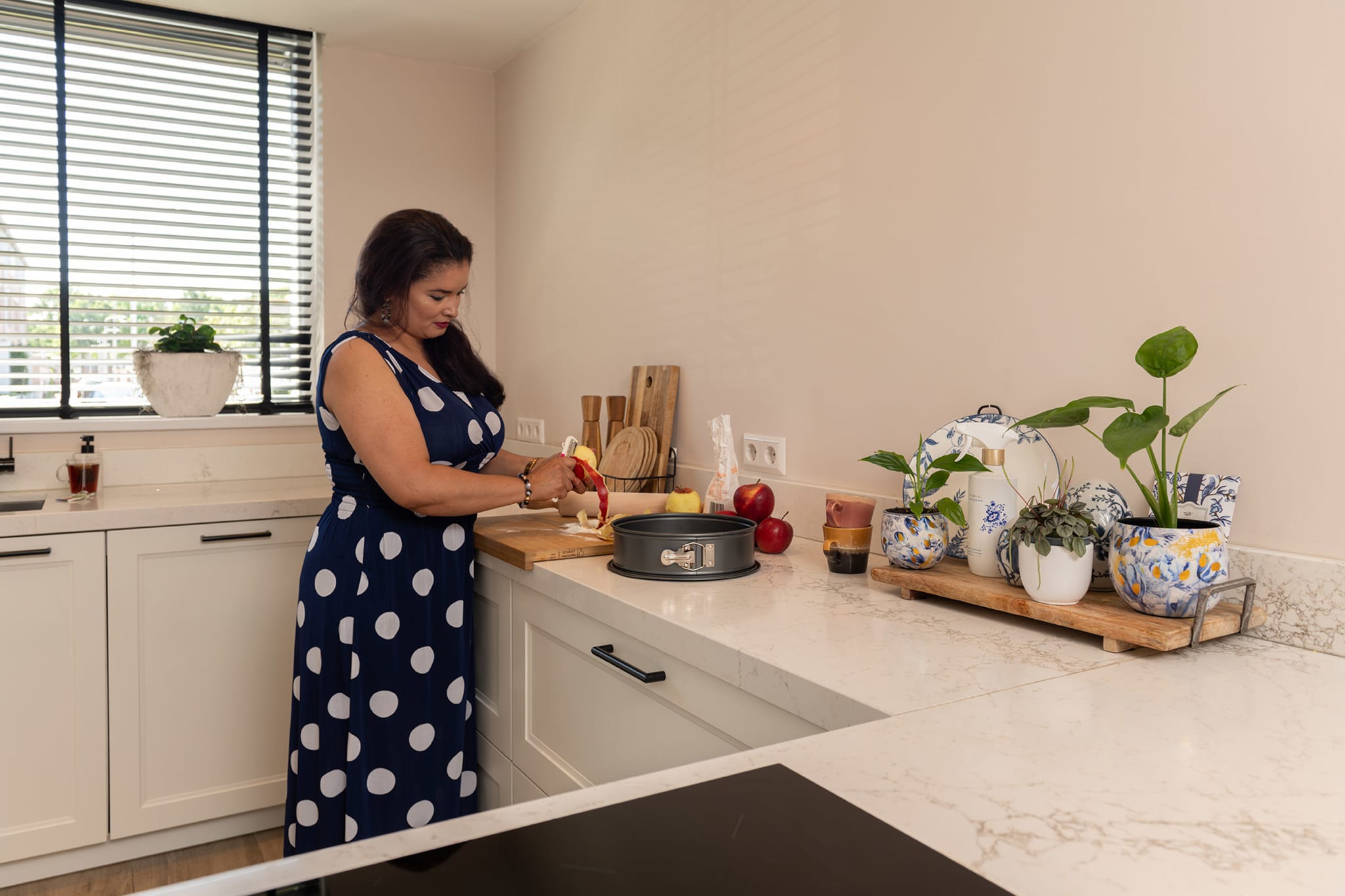 Tamara snijdt appels op het marmerlook werkblad, naast een springvorm en houten planken