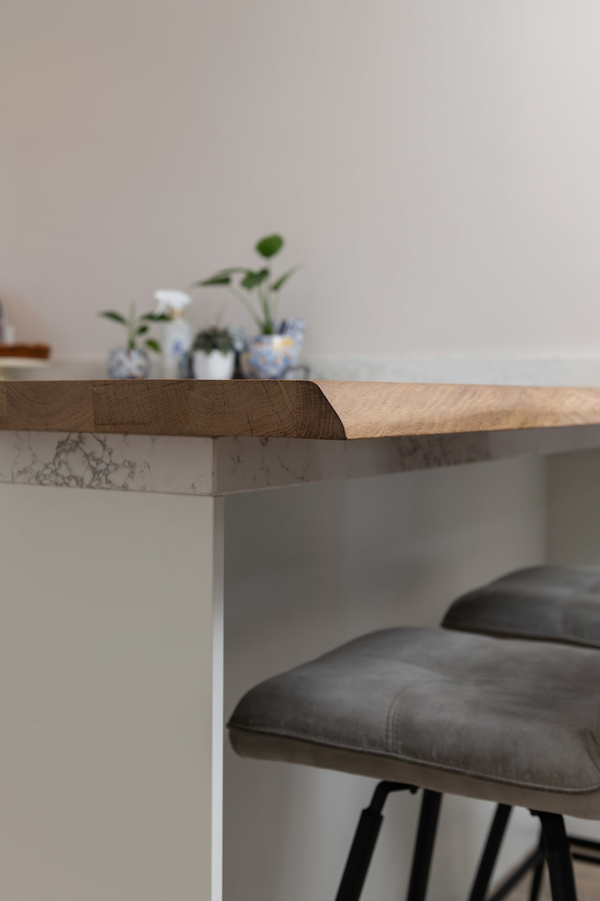 Detail van de eiken bartafel met een watervalzijkant in marmerlook en grijze barkrukken