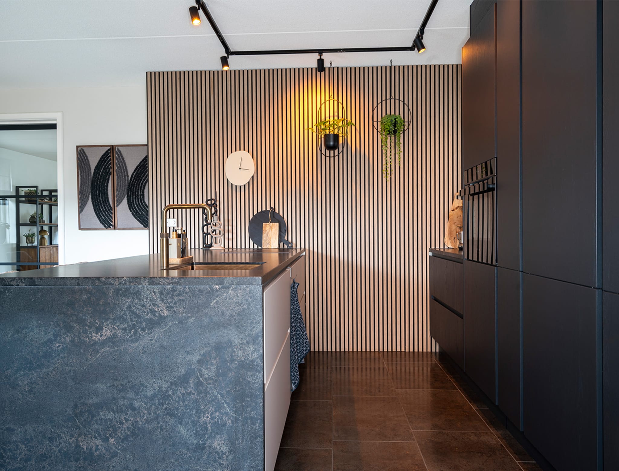 Keuken met marmerlook kookeiland, donkere kasten en houten lattenwand
