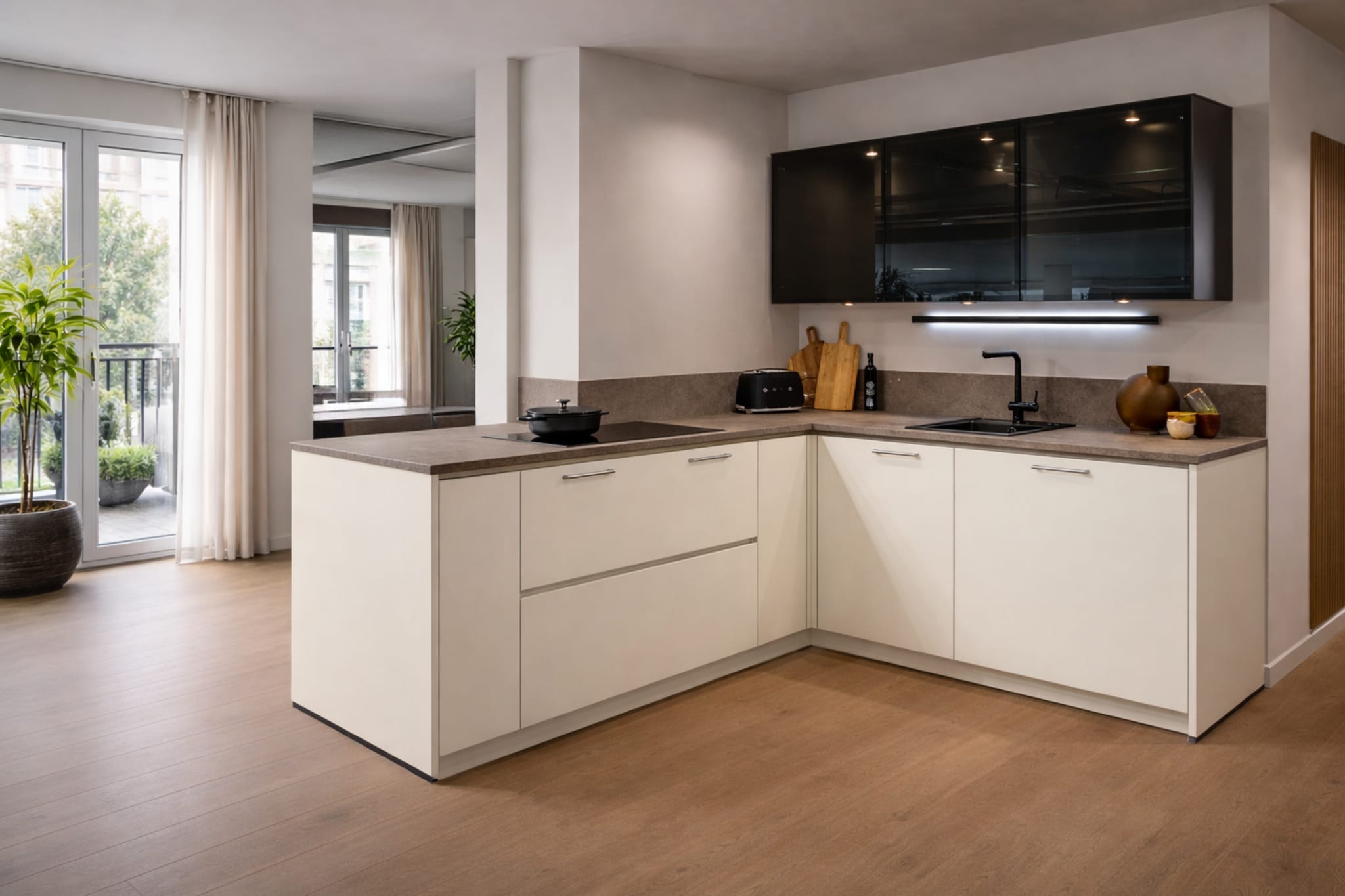 Moderne L-keuken met kookeiland, beige matte fronten, donker composiet werkblad en handgrepen.