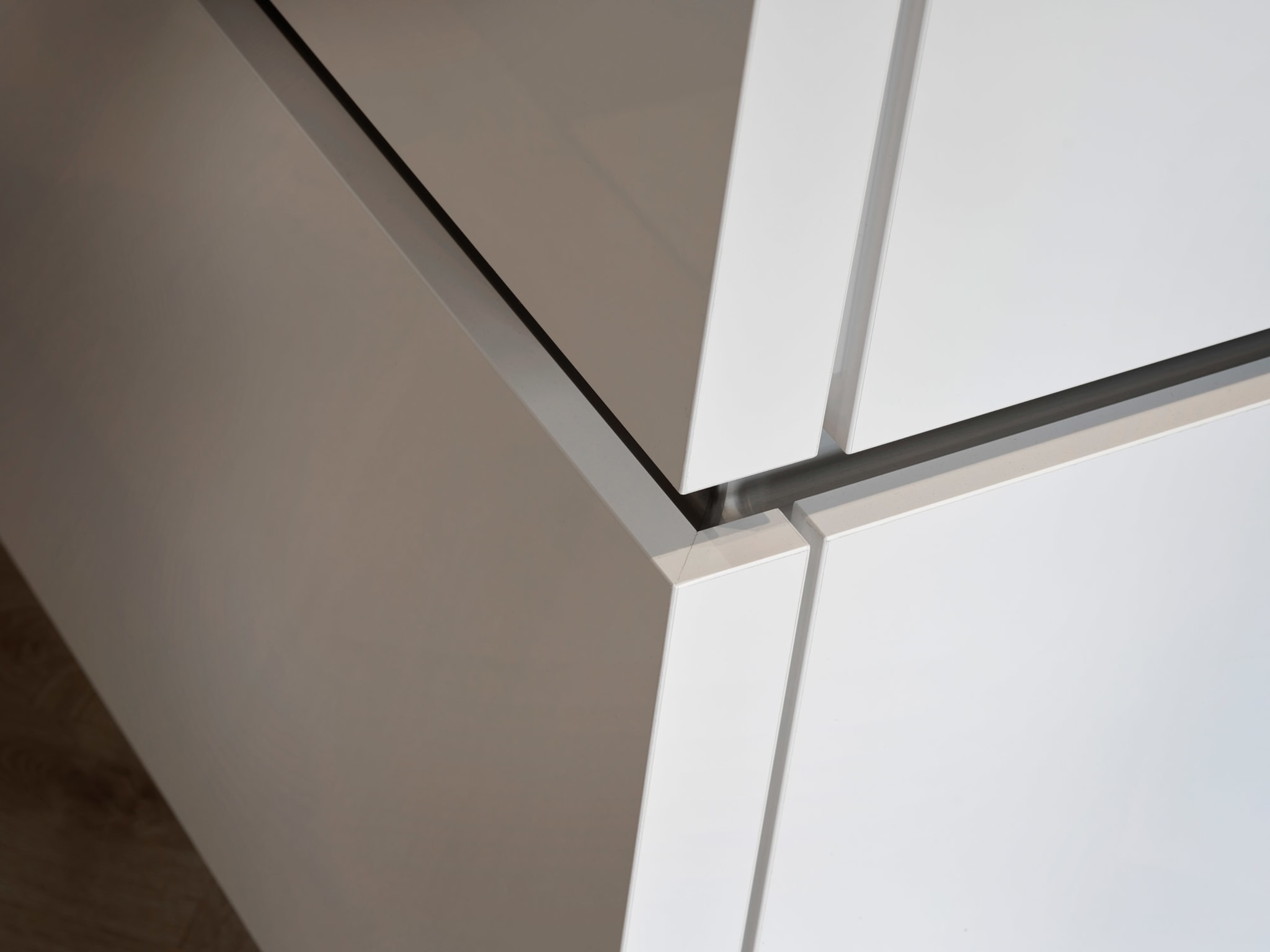 Close-up van een moderne Kitchen4All keuken met witte en grijze matte fronten en strakke greeplijsten.