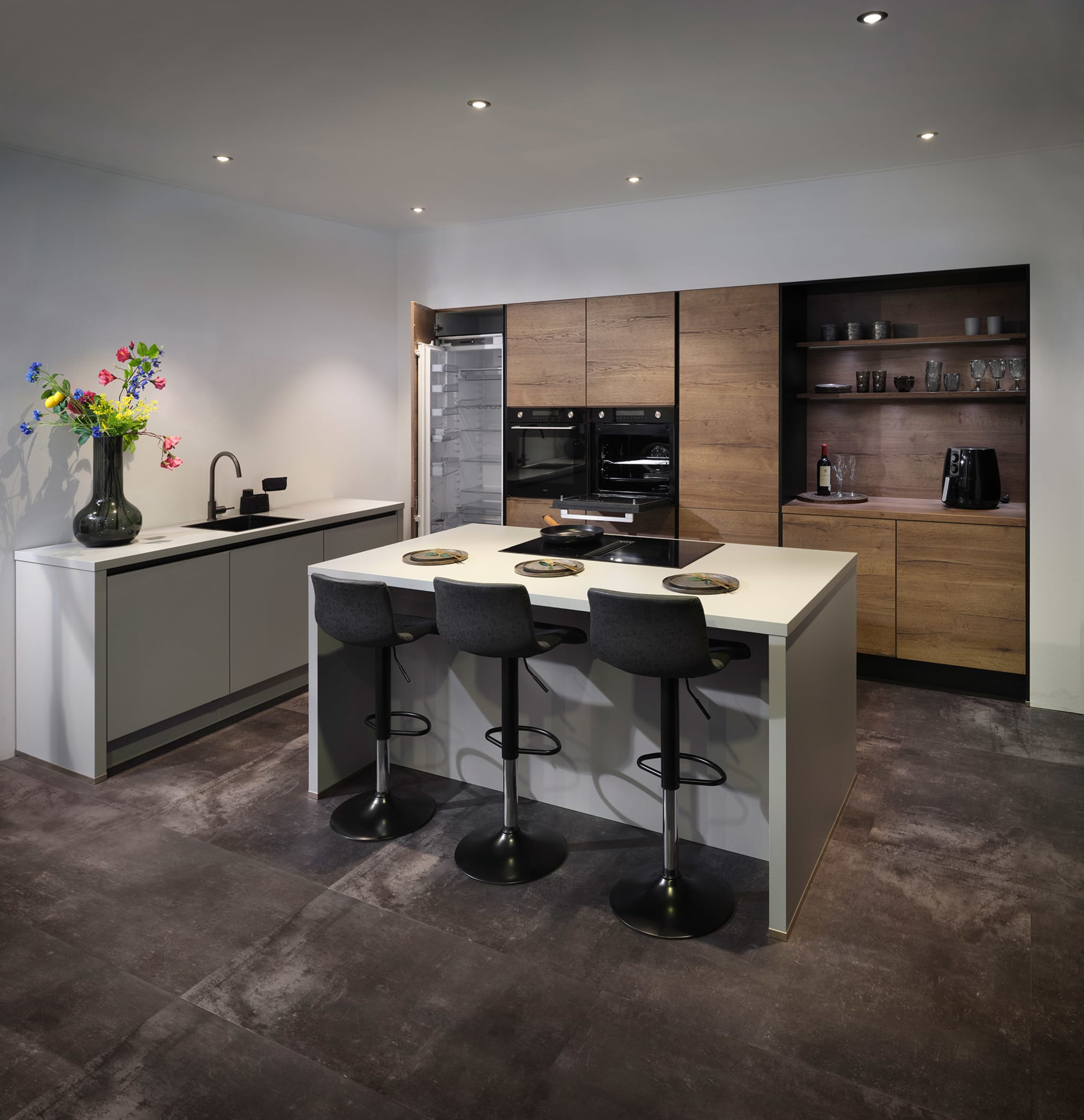 Moderne Kitchen4All eilandkeuken Structuur warm met greeploze houtlook en grijze fronten, wit composiet werkblad.