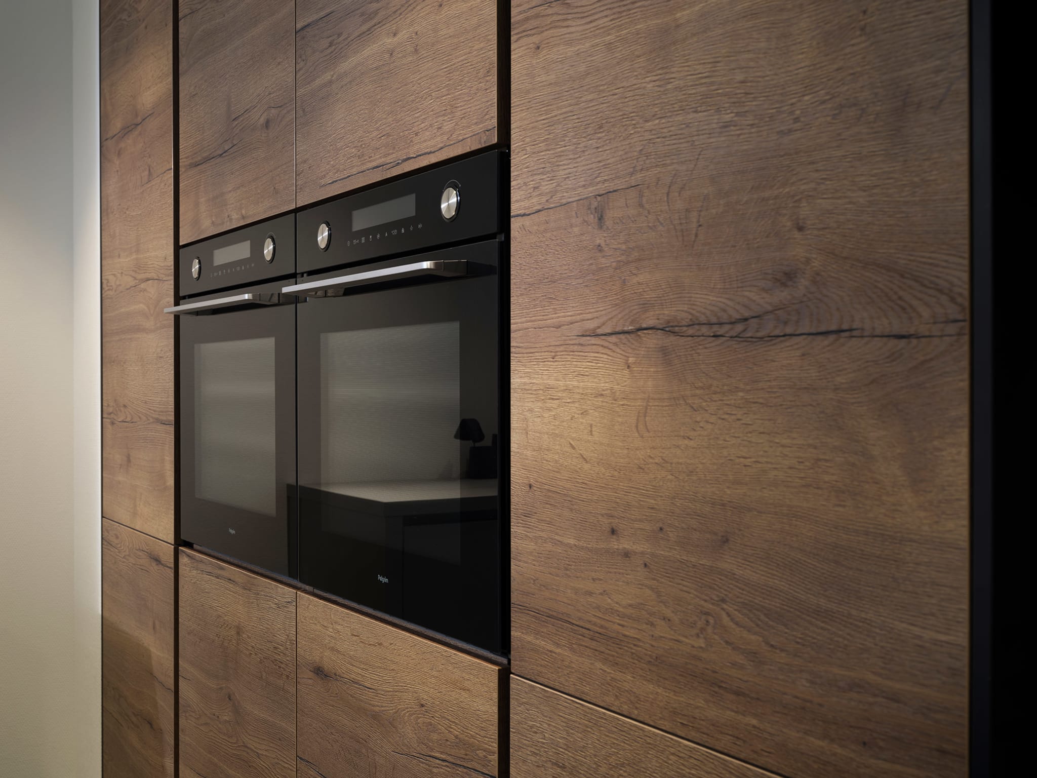 Moderne Kitchen4All keuken met warme houtlook fronten en twee ingebouwde ovens.