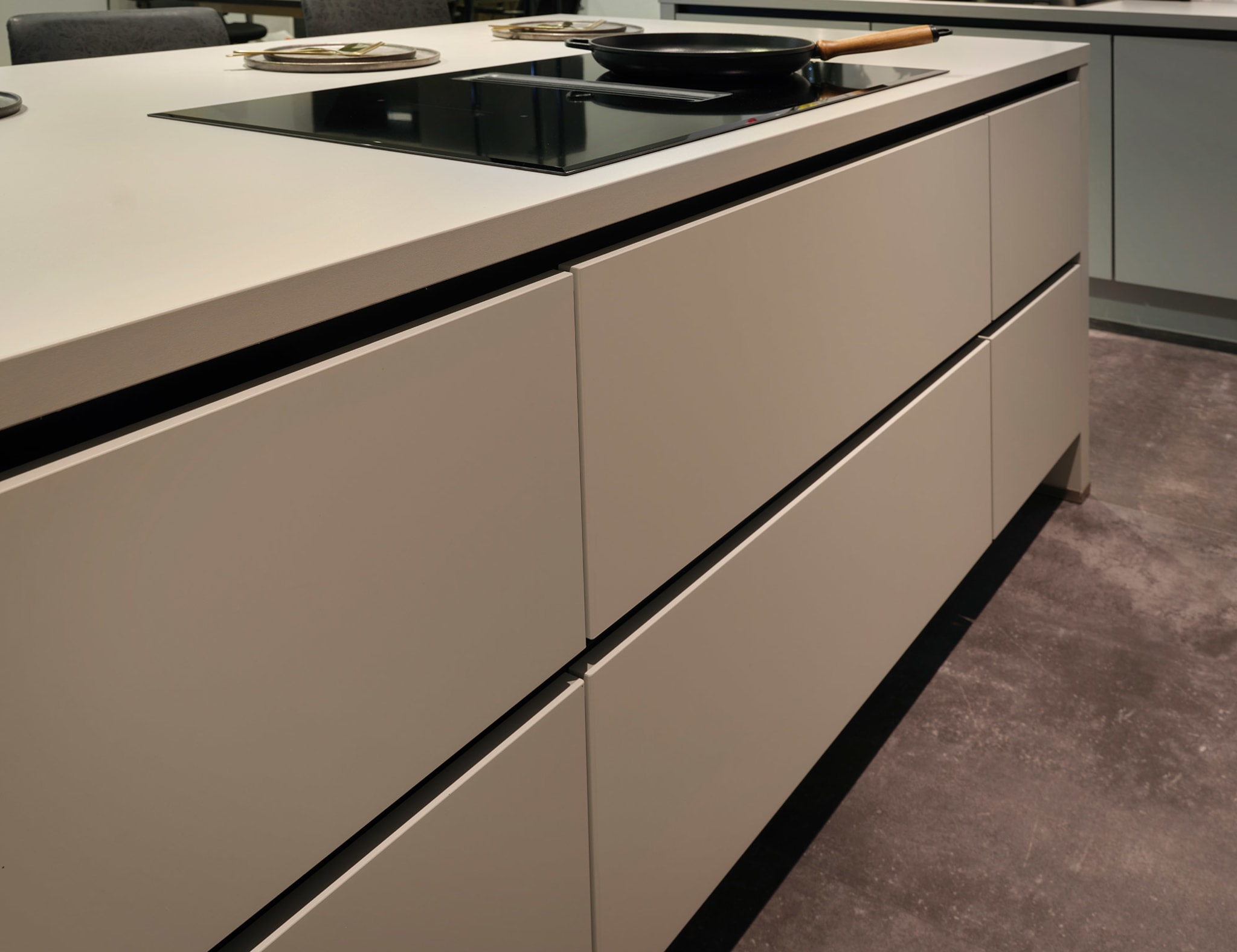 Moderne Kitchen4All eilandkeuken Structuur warm met matgrijze fronten, greeplijsten en een grijs composiet werkblad.