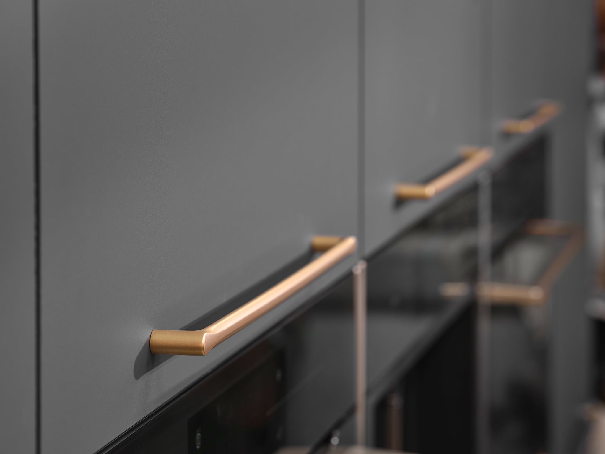 Close-up van een moderne Kitchen4All Contrast chique keuken met matte grijze fronten en gouden handgrepen.