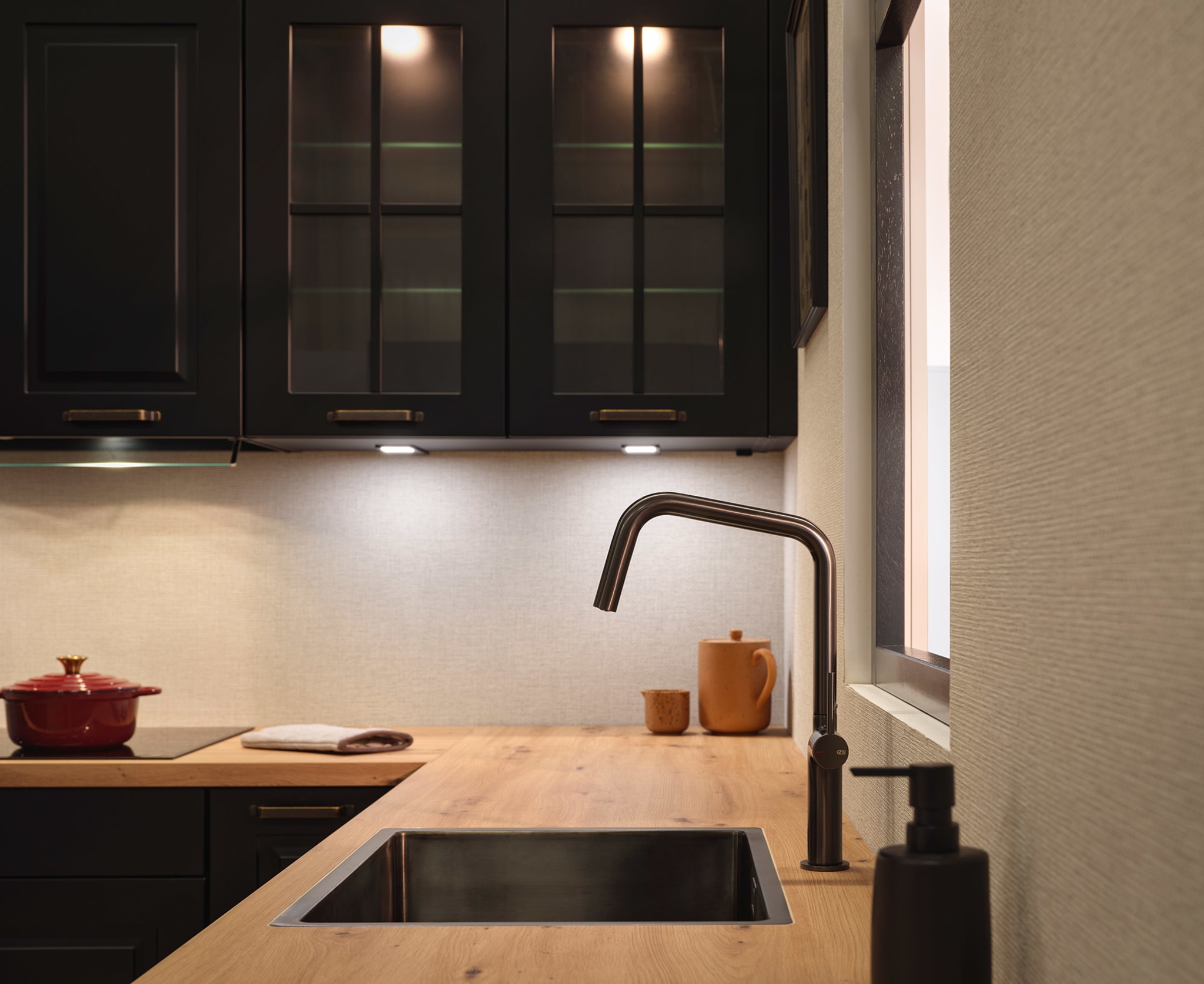 Een nostalgische Kitchen4All L-keuken met donkere kaderfronten, houten werkblad en zwarte kraan.
