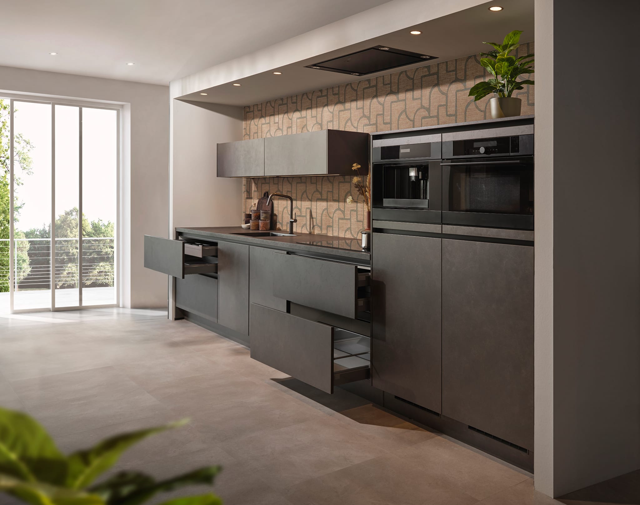 Moderne greeploze Kitchen4All keuken met donkergrijze matte fronten en een keramiek werkblad in betonlook.