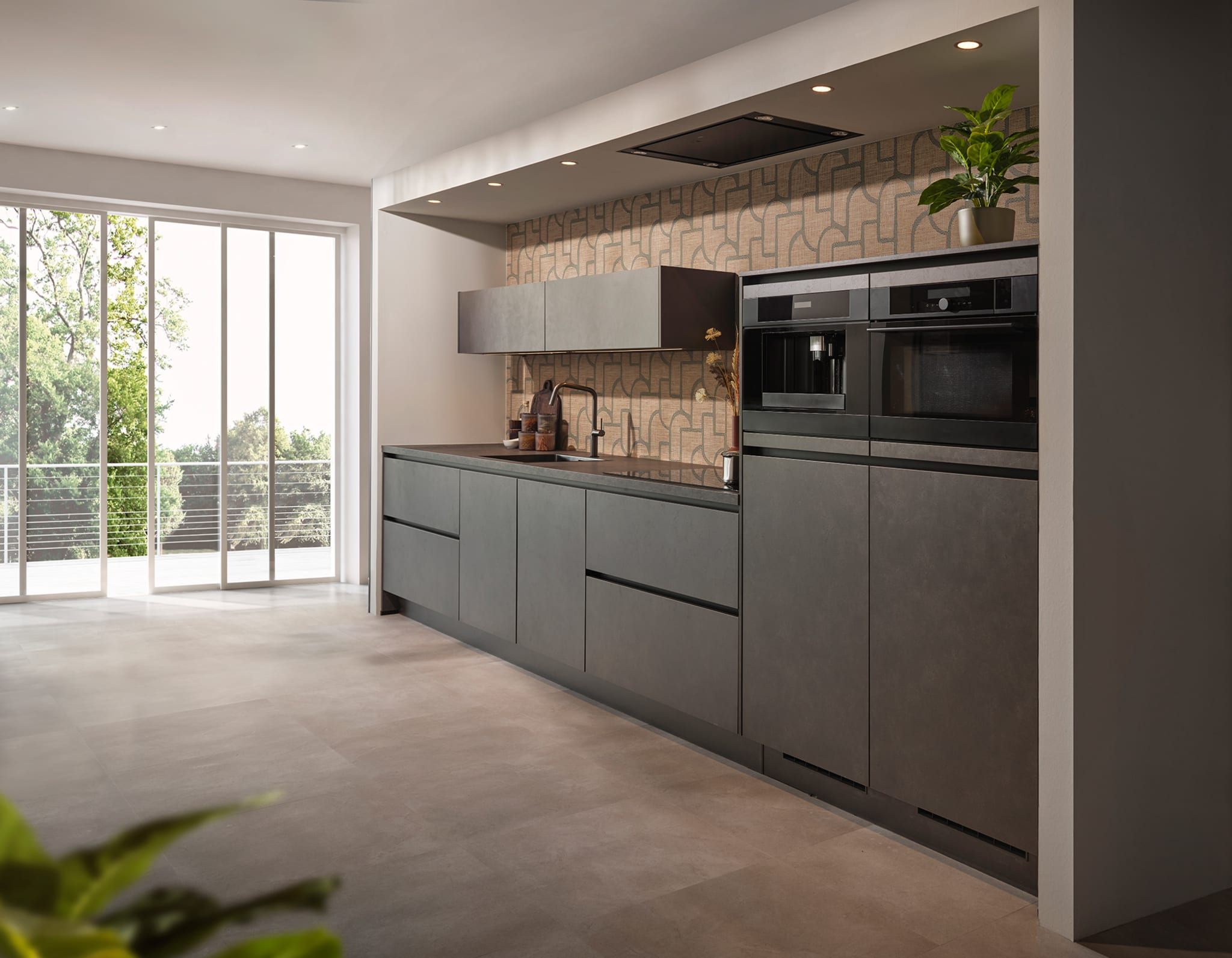 Stijlvolle stoere greeploze keuken met matte grijze fronten en donker composiet werkblad in een open ruimte.