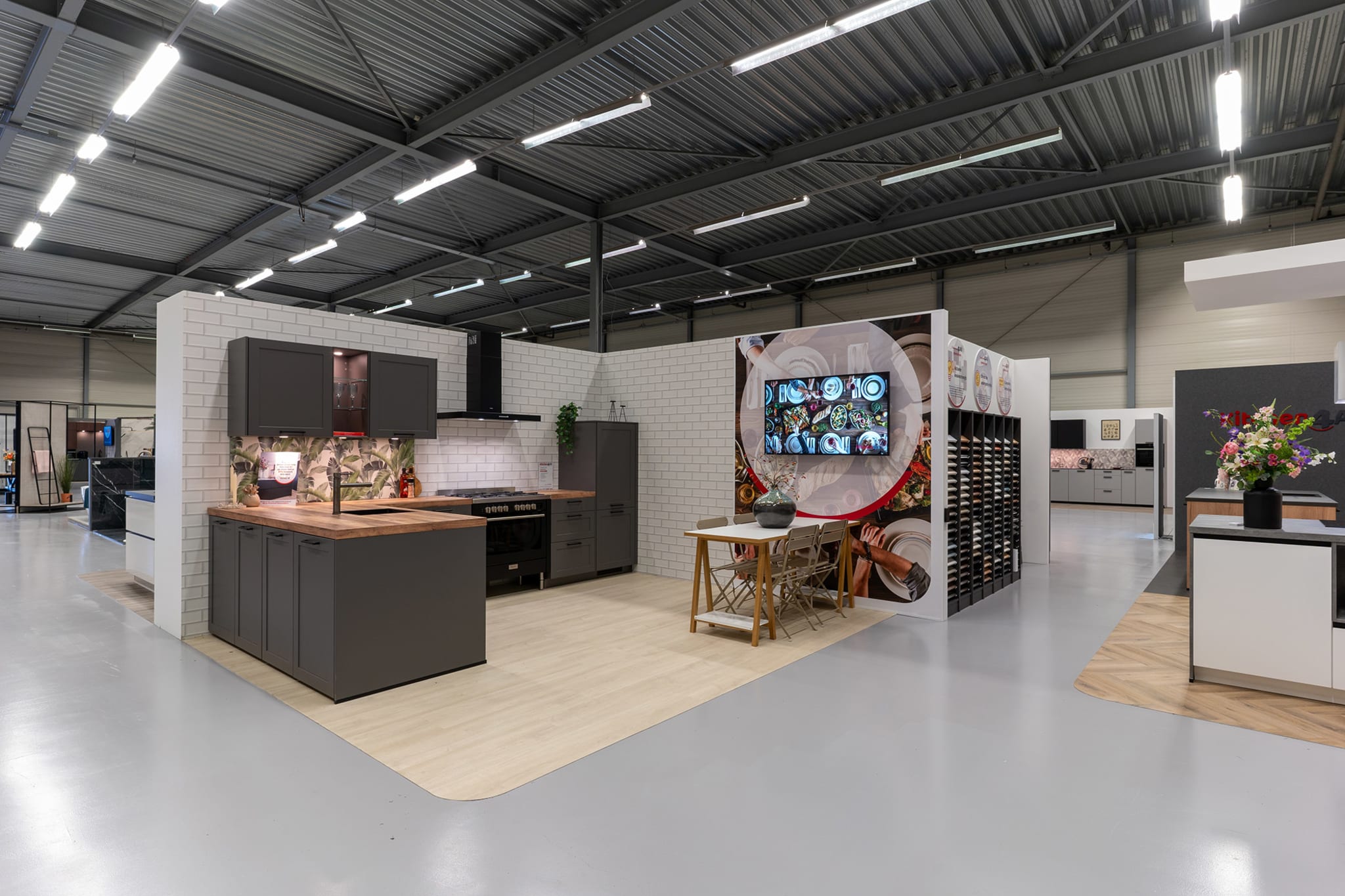 Keukenopstellingen met donkere fronten en een stalenrek in de Kitchen4All-winkel