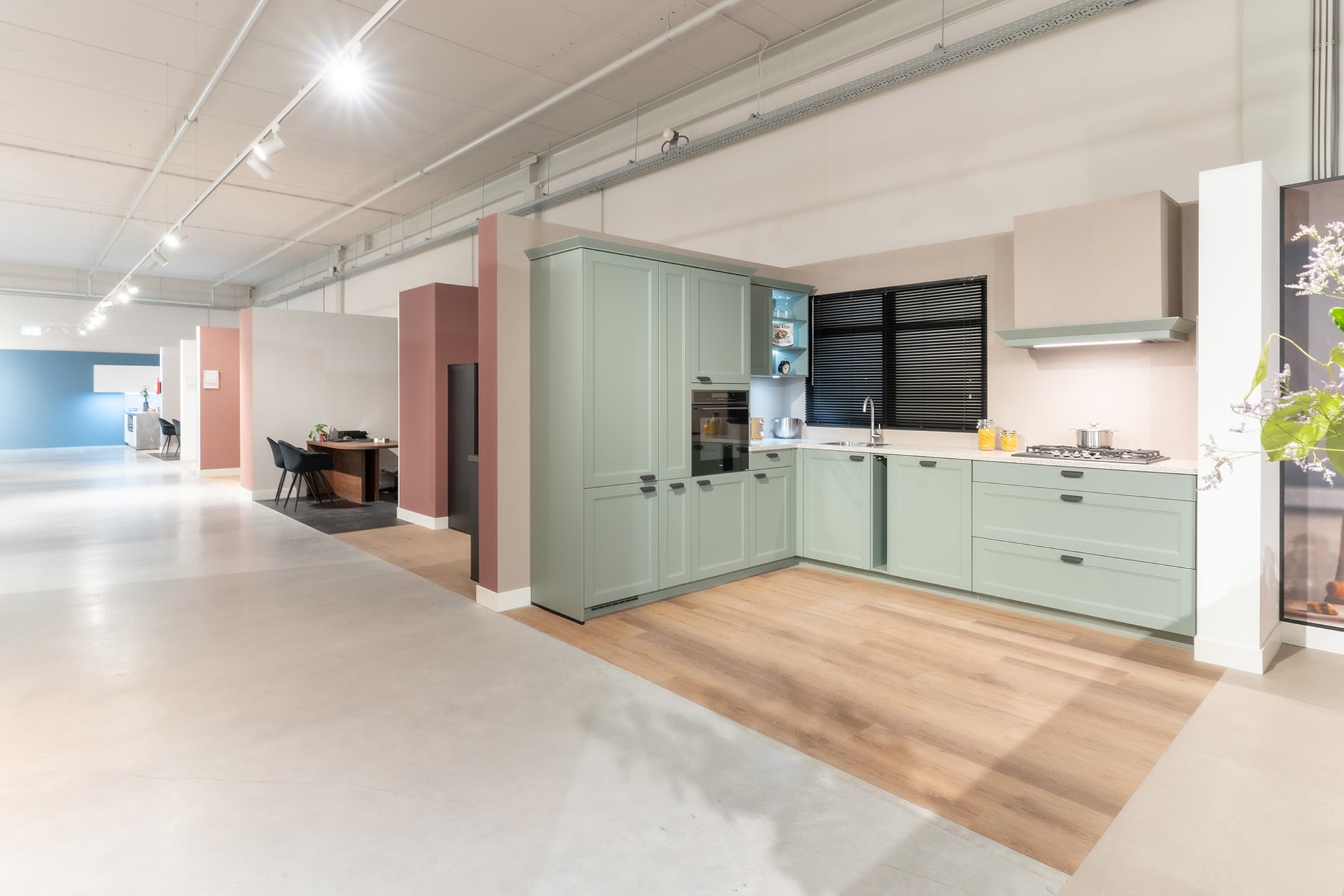 Zachtgroene keuken met houten vloer en zwarte raamdetails