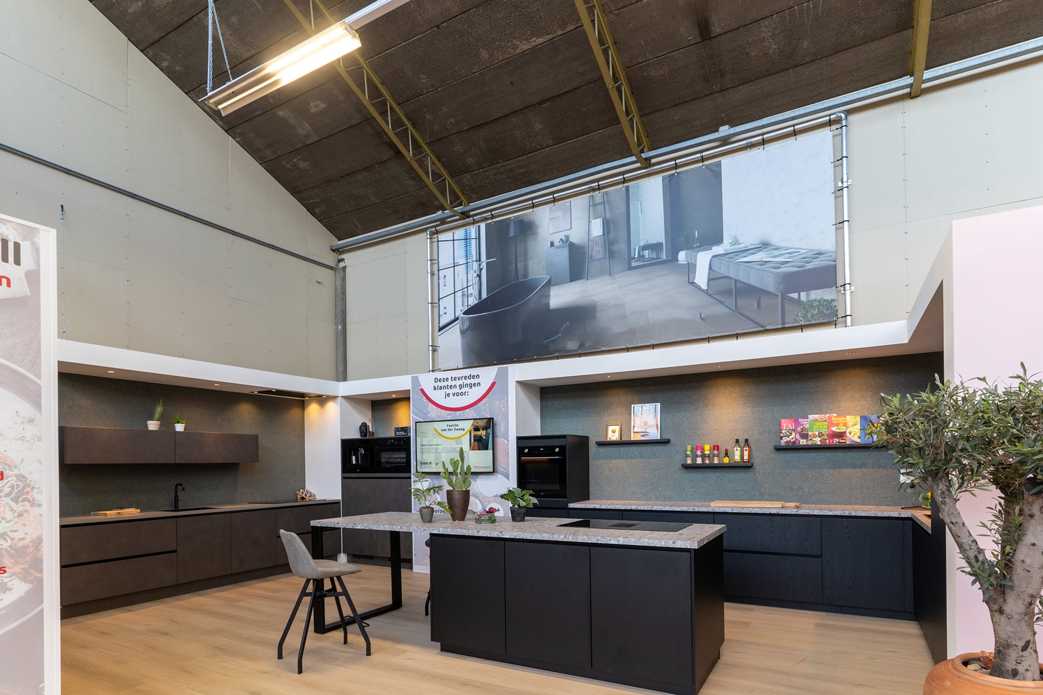Moderne matzwarte eilandkeuken met greeploze fronten en donker composiet werkblad in de Kitchen4All-winkel