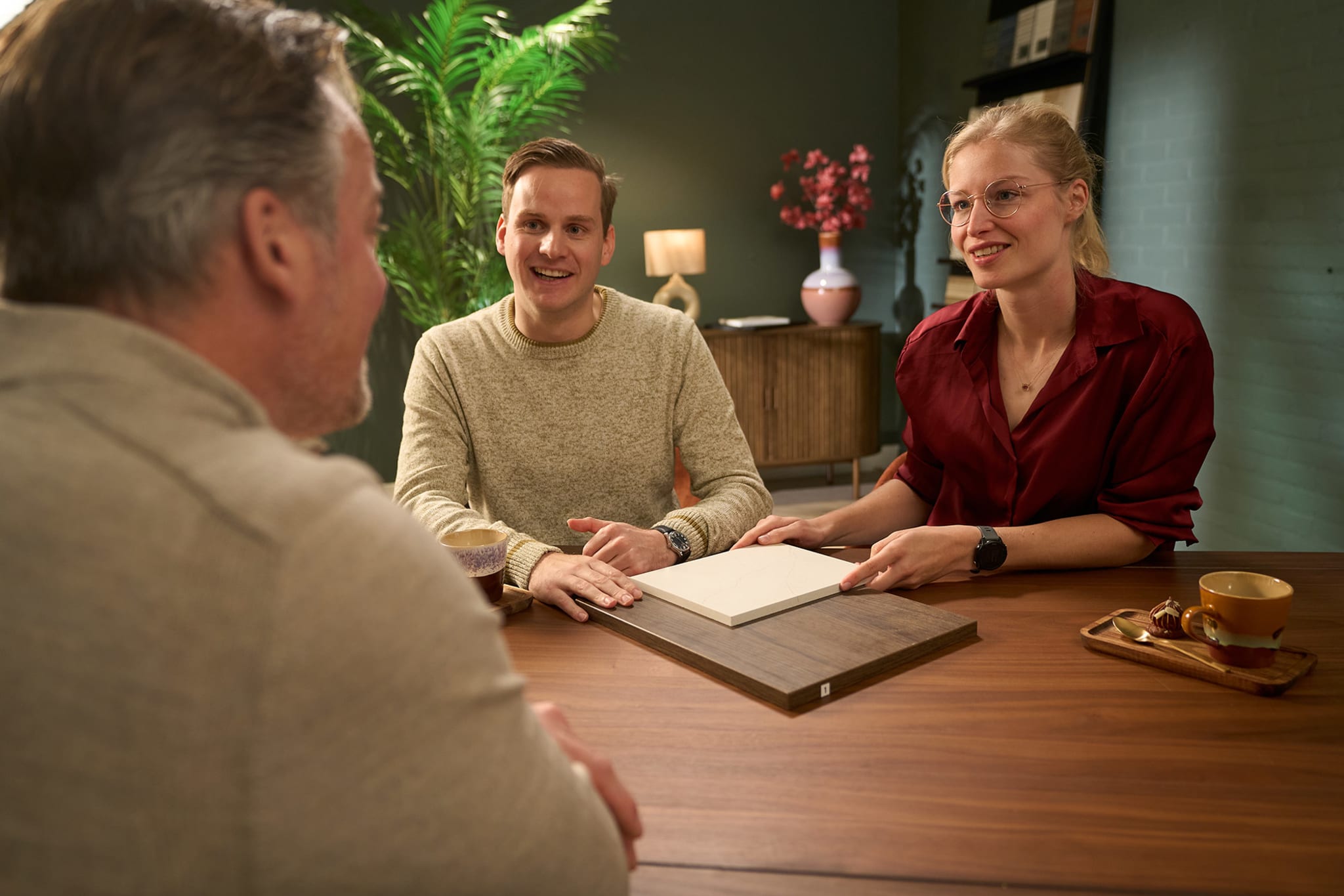 Kitchen4All-adviseur bekijkt materiaalvoorbeelden met een stel aan tafel