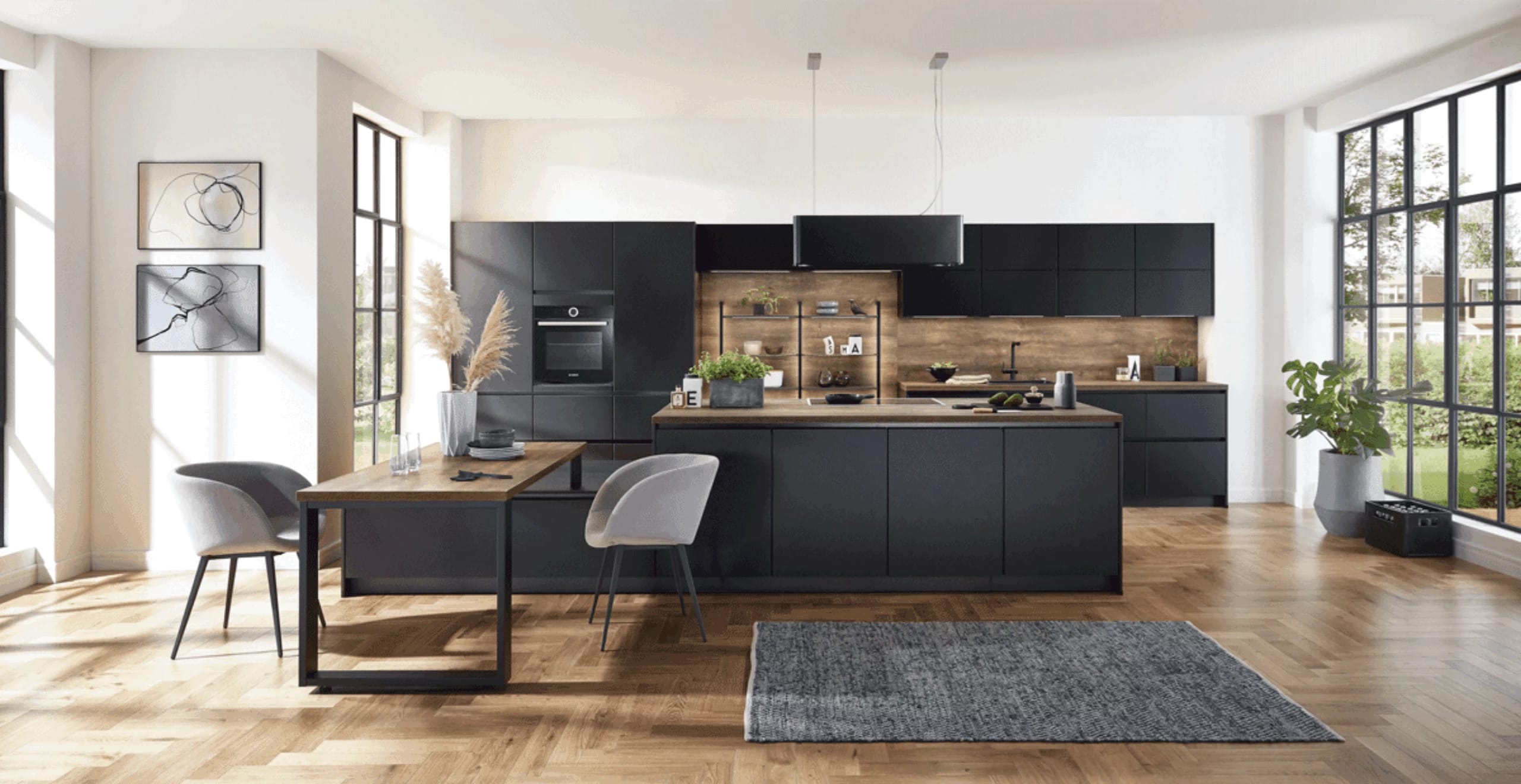 Mat zwarte keuken met houten achterwand en eettafel in een lichte ruimte met stalen ramen