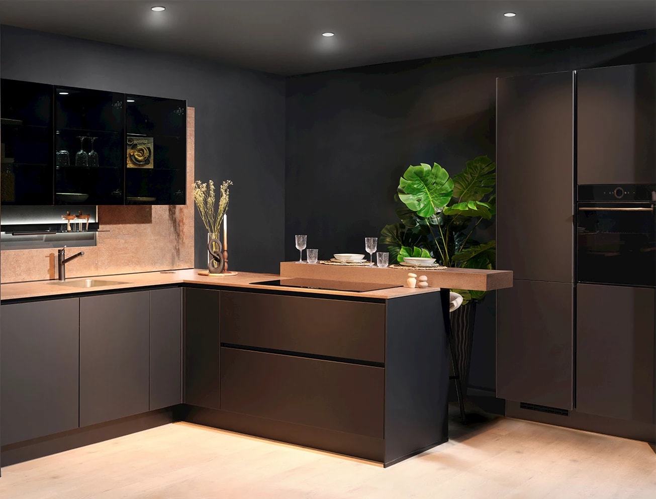 Donkere L-keuken met een houten bar als verlengstuk, gedekt met glazen en borden