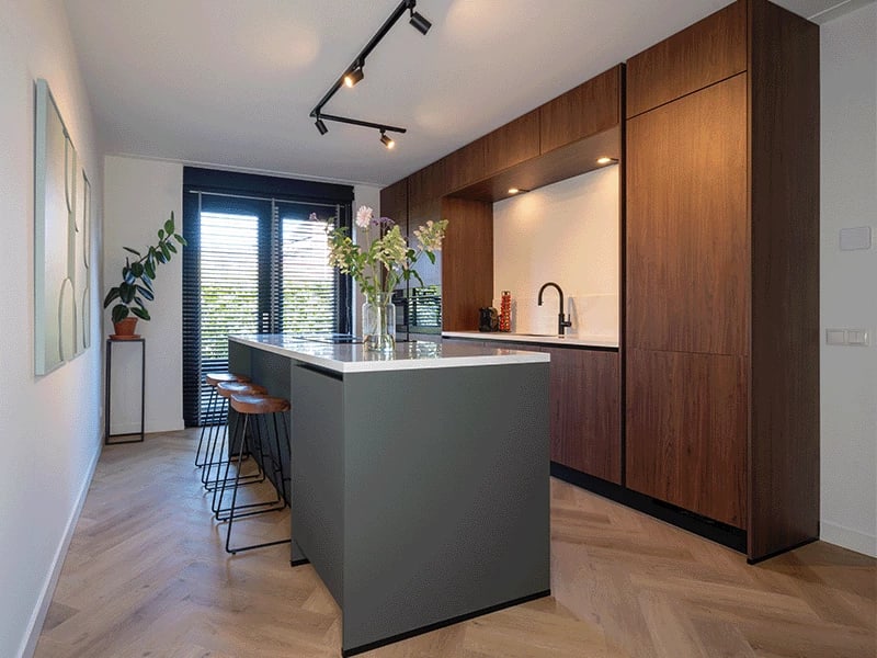 Groene keuken met houten kasten, een grote kamerplant en open schappen