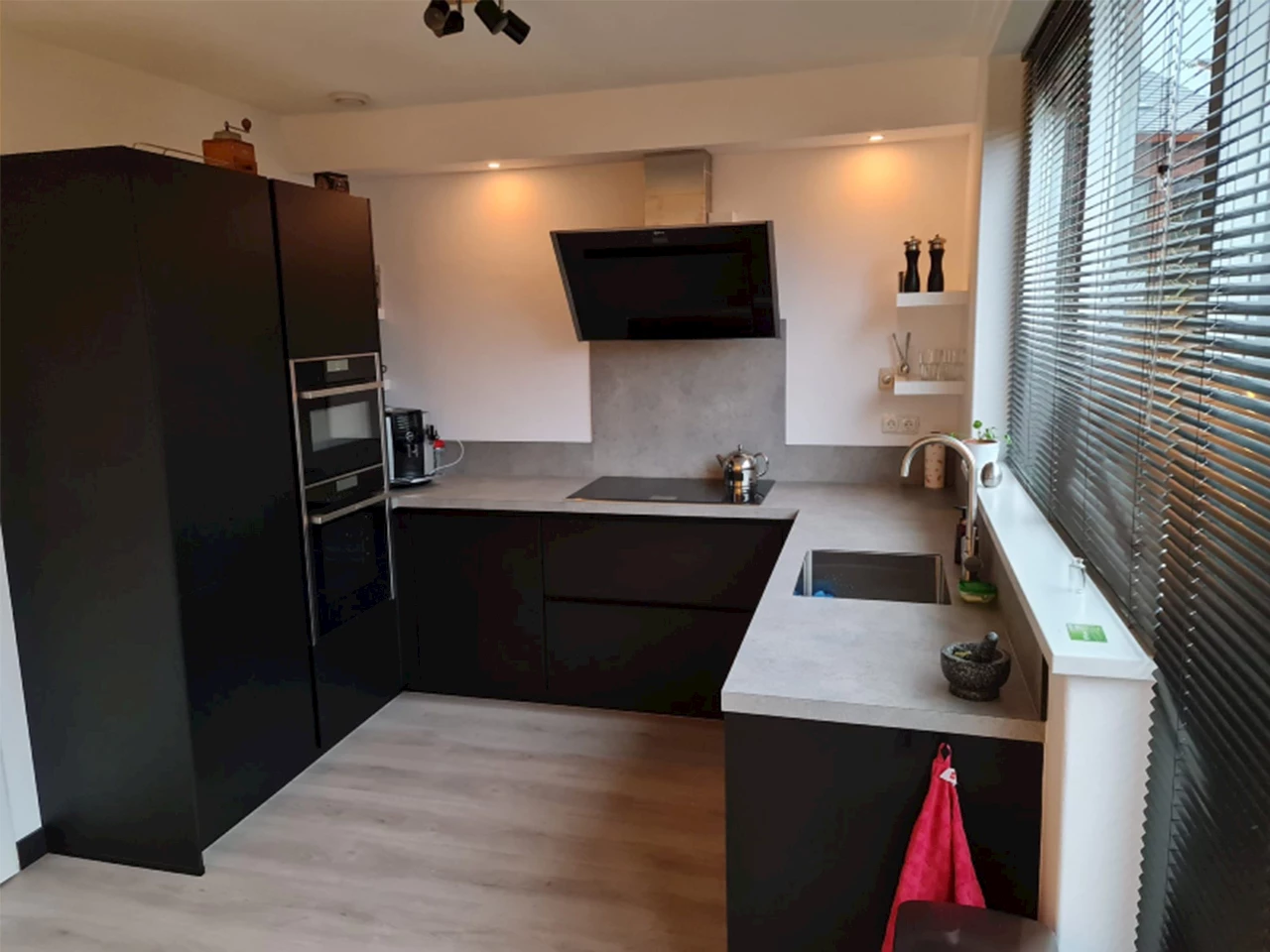 Zwarte u-keuken met betonlook blad