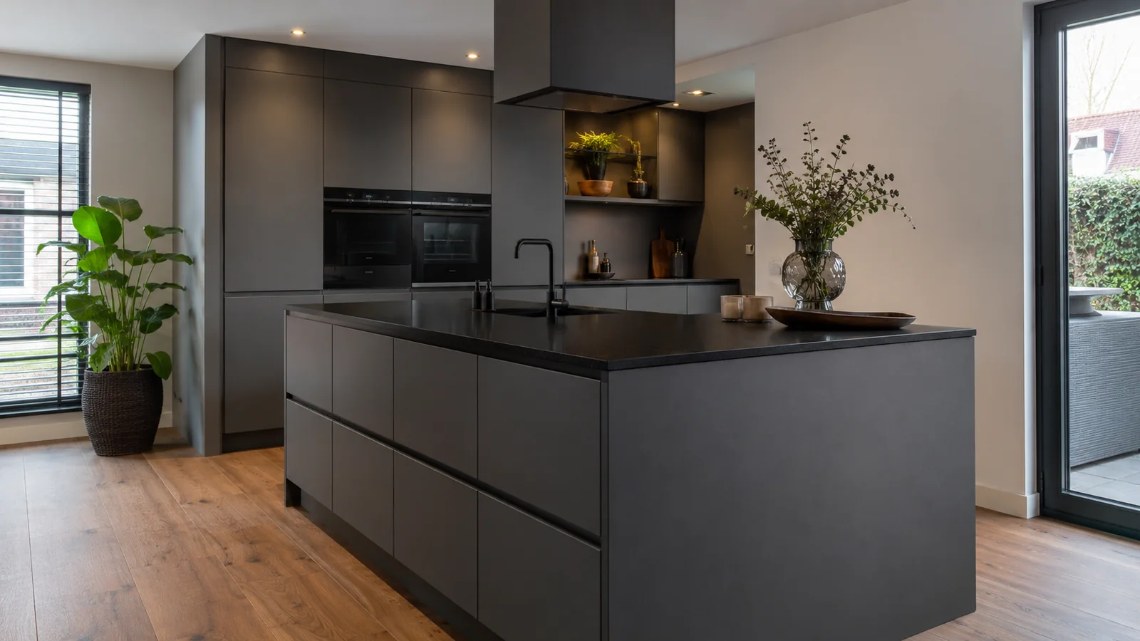 Donkergrijze keuken met een zwart werkblad en kookeiland