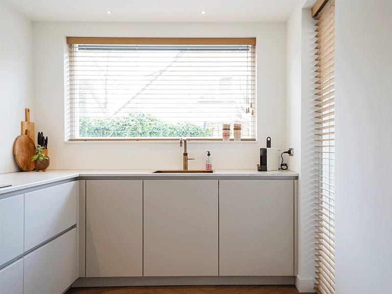 Matte witte keuken met warme houten accenten en een lichte vloer