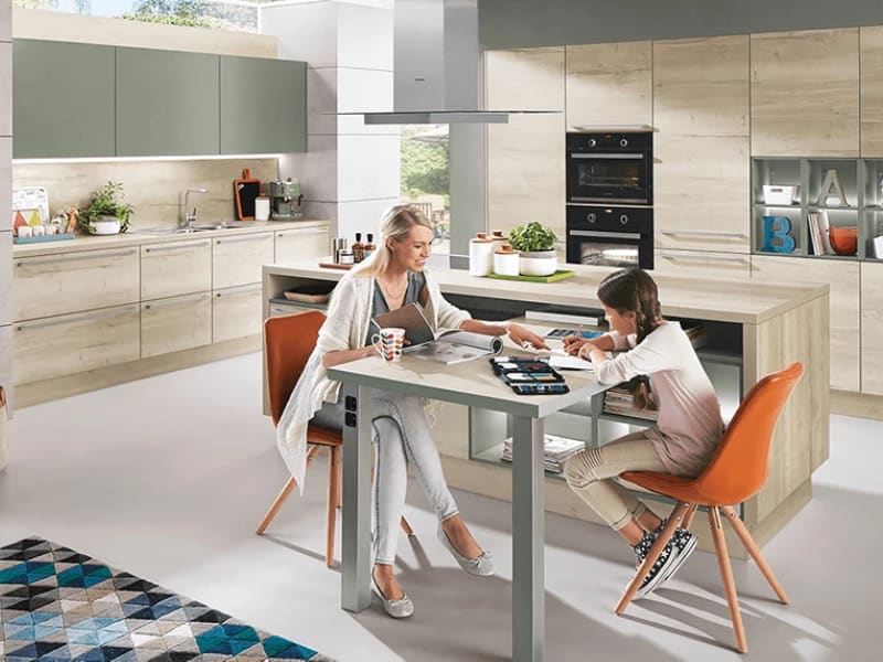 Gezin in een keuken met mintgroene bovenkasten en houten onderkasten