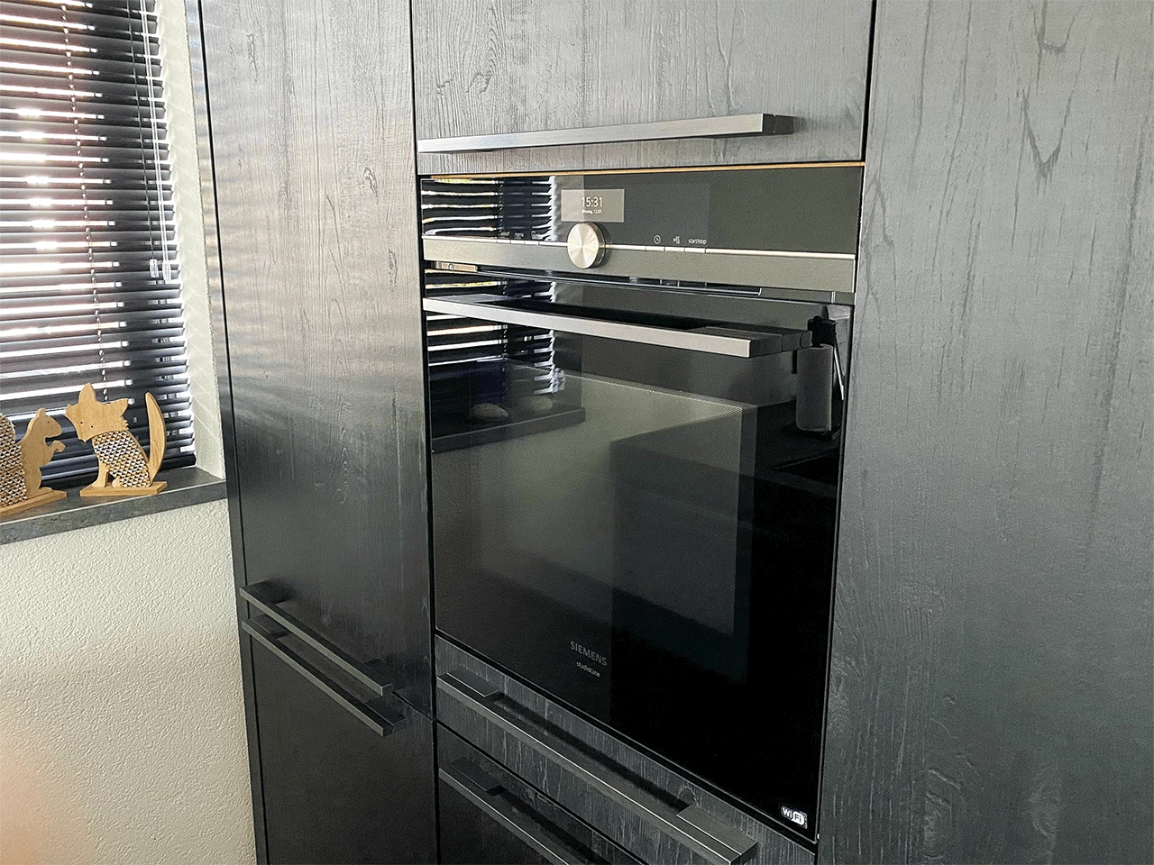 Inbouwoven met rvs greep in een zwarte keuken met houtstructuur