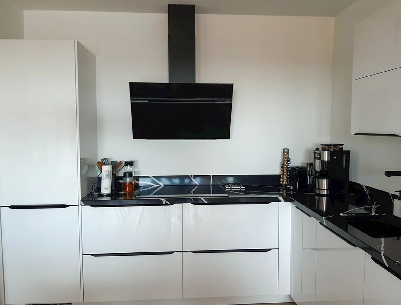 Witte keuken met een zwart werkblad, zwarte afzuigkap en zwarte accenten